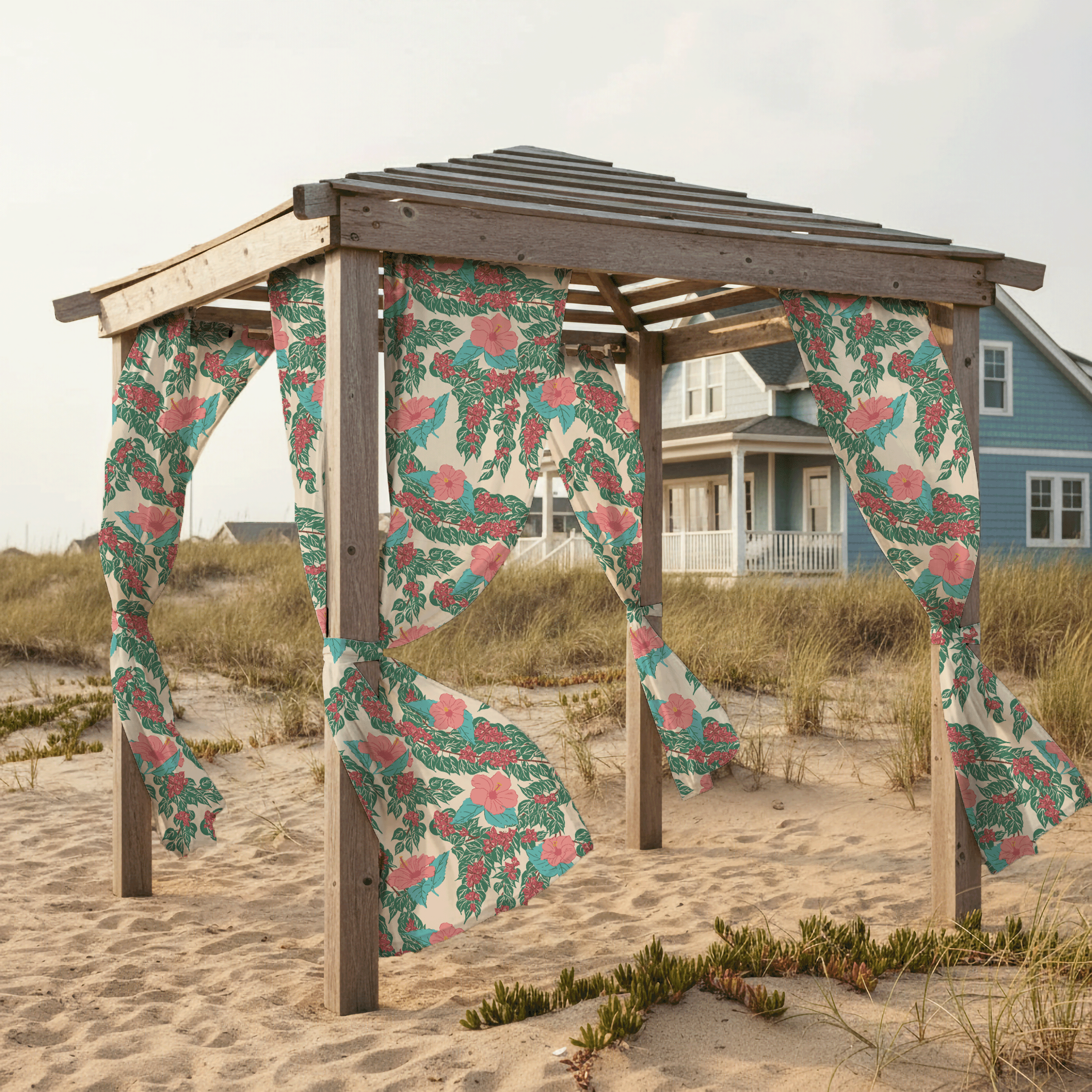 Outdoor fabric panels printed with large tropical floral surface pattern flowing from a wooden beach shelter in a coastal dune setting.