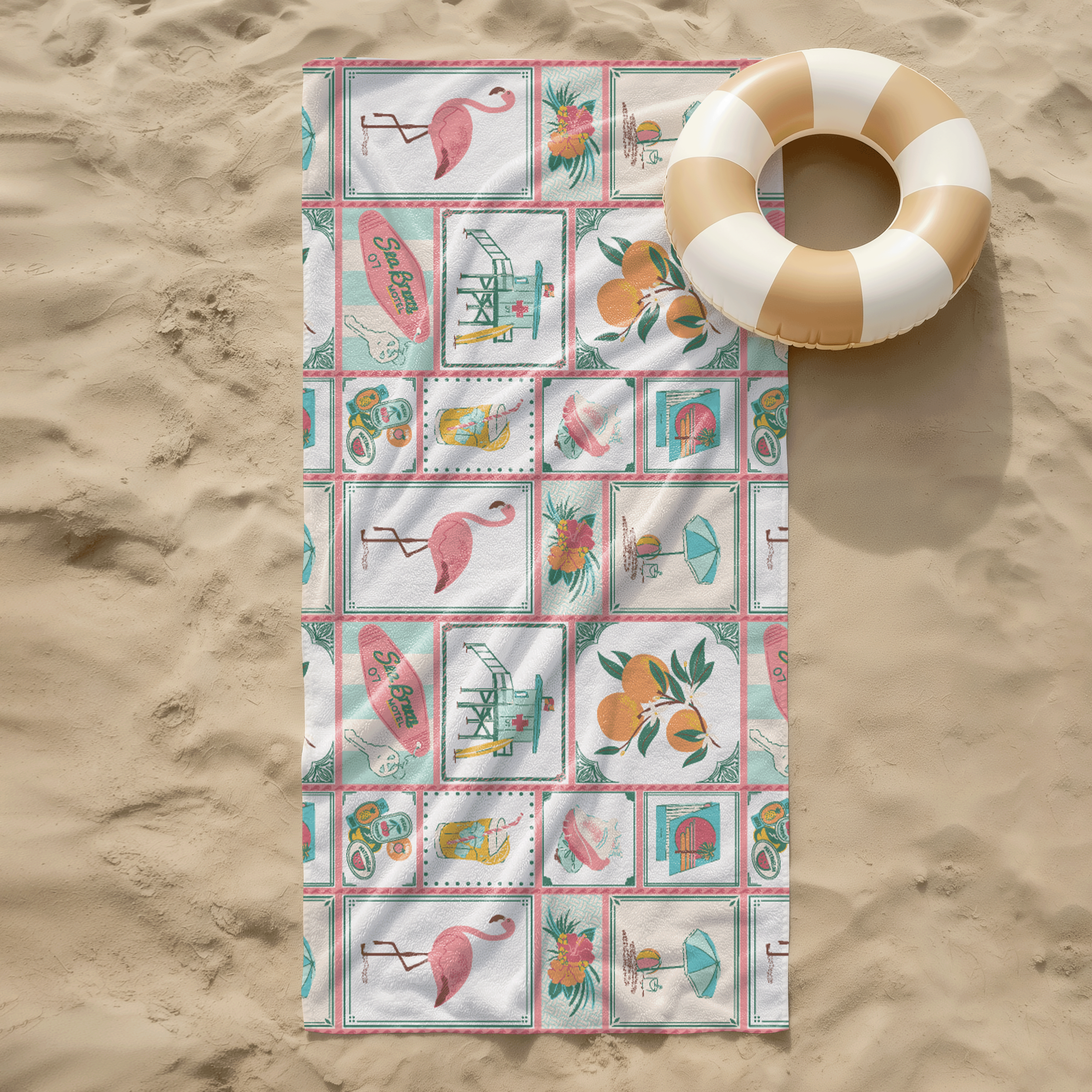 Beach towel laid on sand featuring colorful seaside motif surface pattern with shells, fruit, and summer icons in aqua and coral palette.
