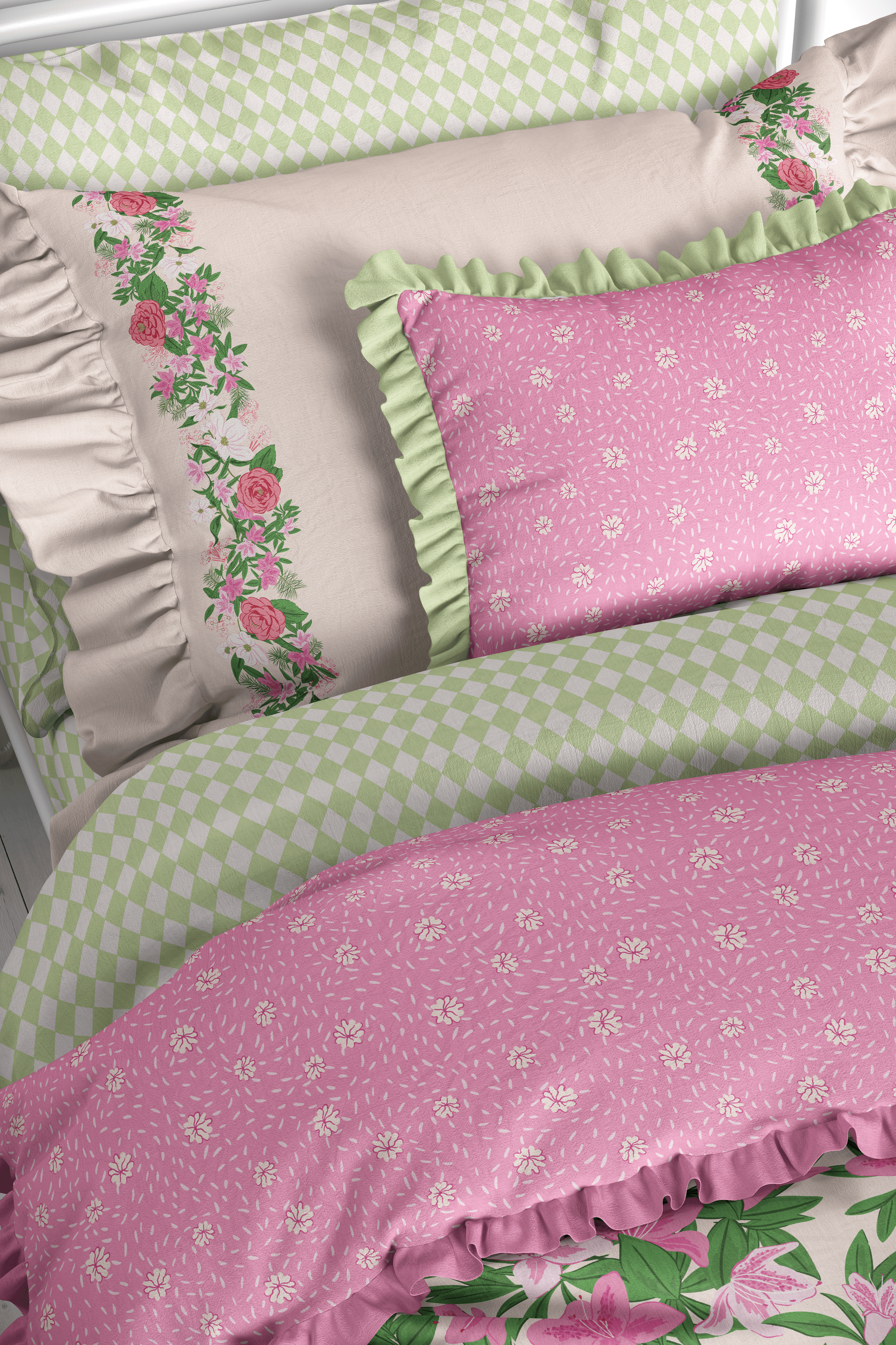 Coordinated bedding ensemble featuring floral border pillowcases paired with geometric and floral fabrics in a pink and green palette.