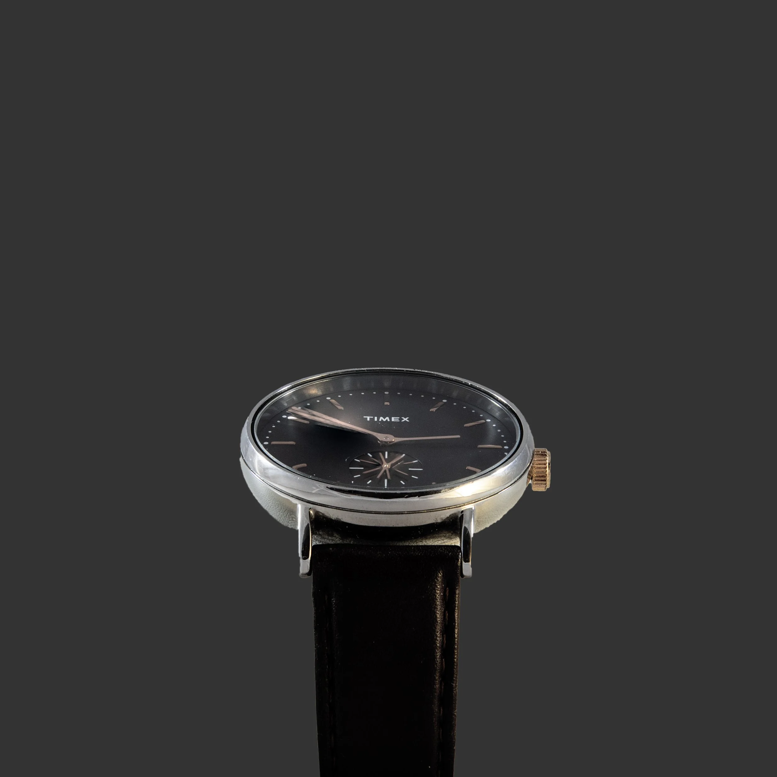 Montre Timex avec un cadran noir et un bracelet en cuir noir. Le fond d'écran est gris foncé.