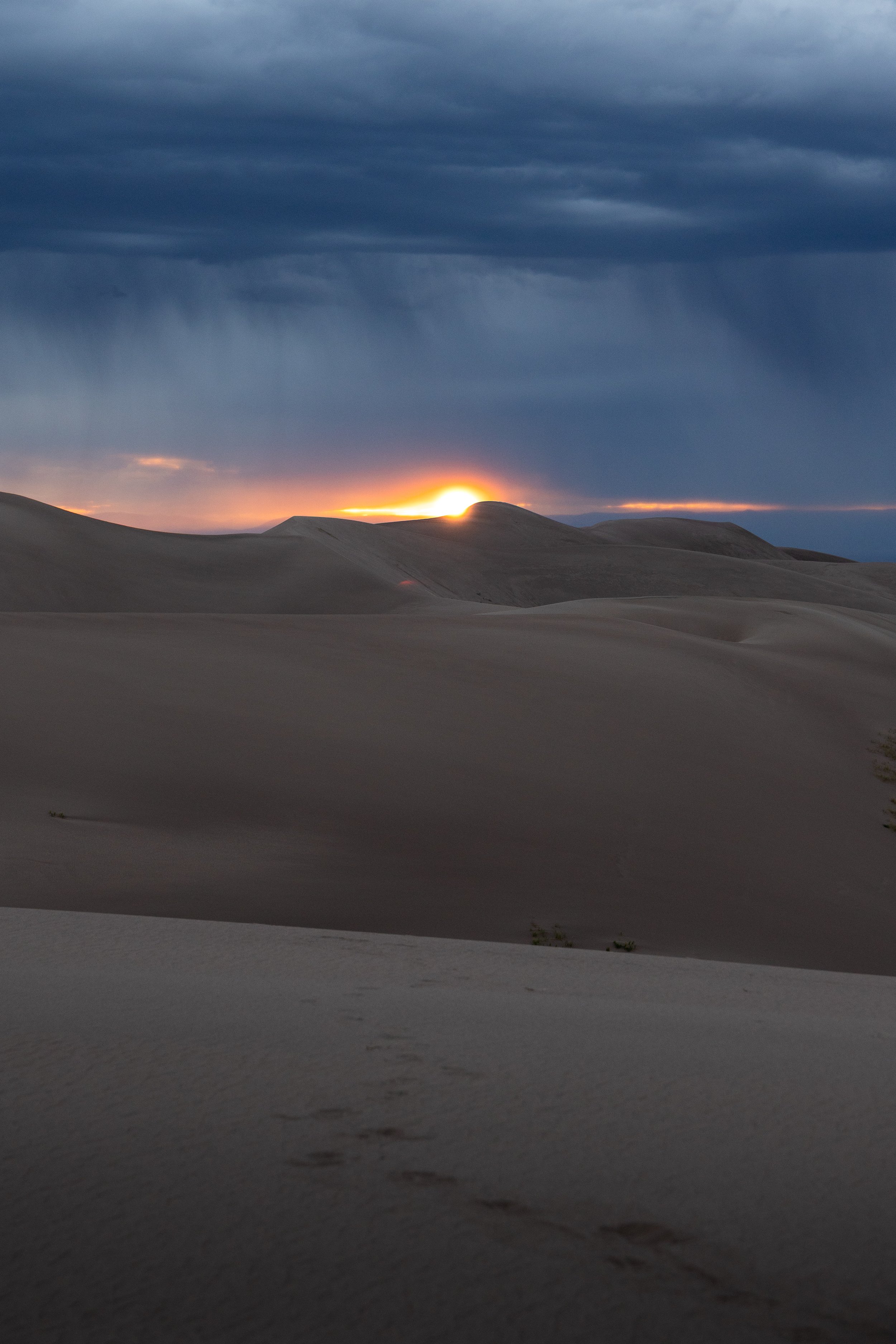 Sunset in the Sand Dunes National Park with rainy clouds overhead.
