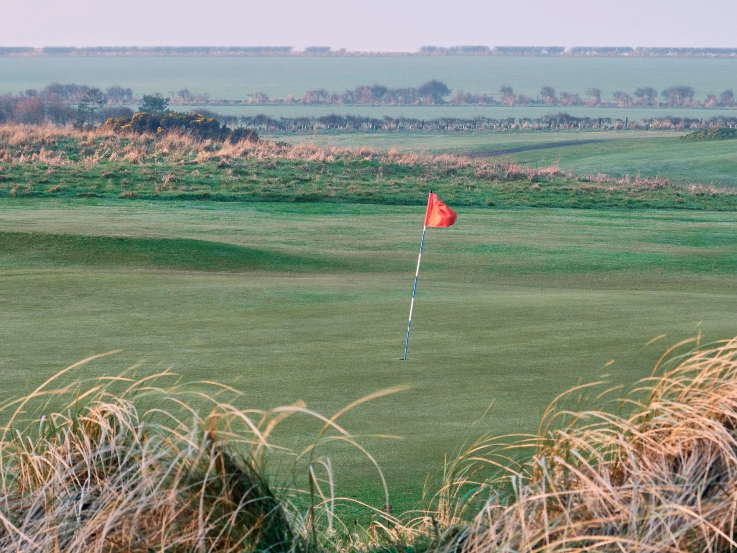 Coastal green golf course with red flag