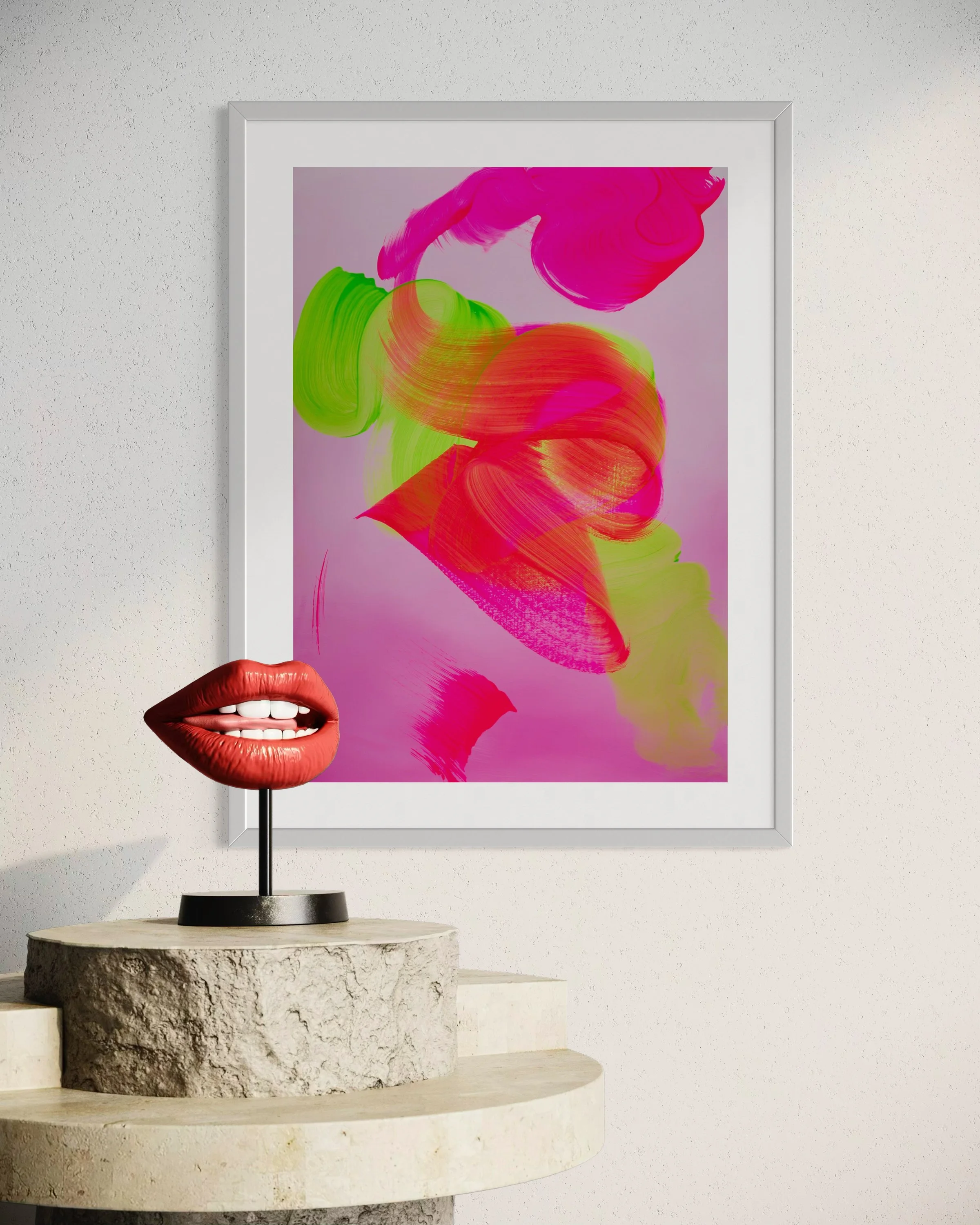 Decorative art display featuring vibrant abstract pink, orange, and green brushstrokes on a purple background, accompanied by a three-dimensional sculpture of lips in red with a black stand, placed on a stone pedestal against a white wall.
