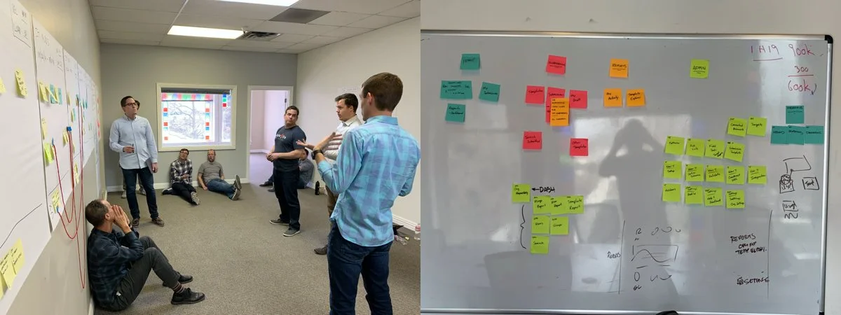 Group of people in a meeting room discussing ideas, with a whiteboard covered in colorful sticky notes and diagrams.