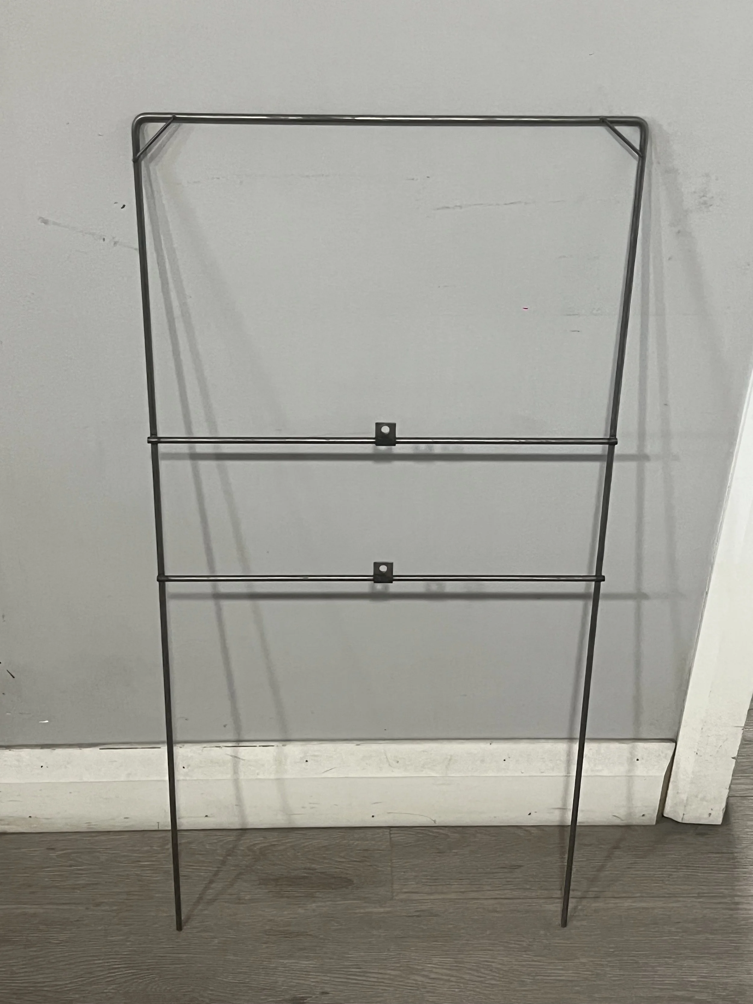 metal rack with two horizontal bars leaning against a wall.