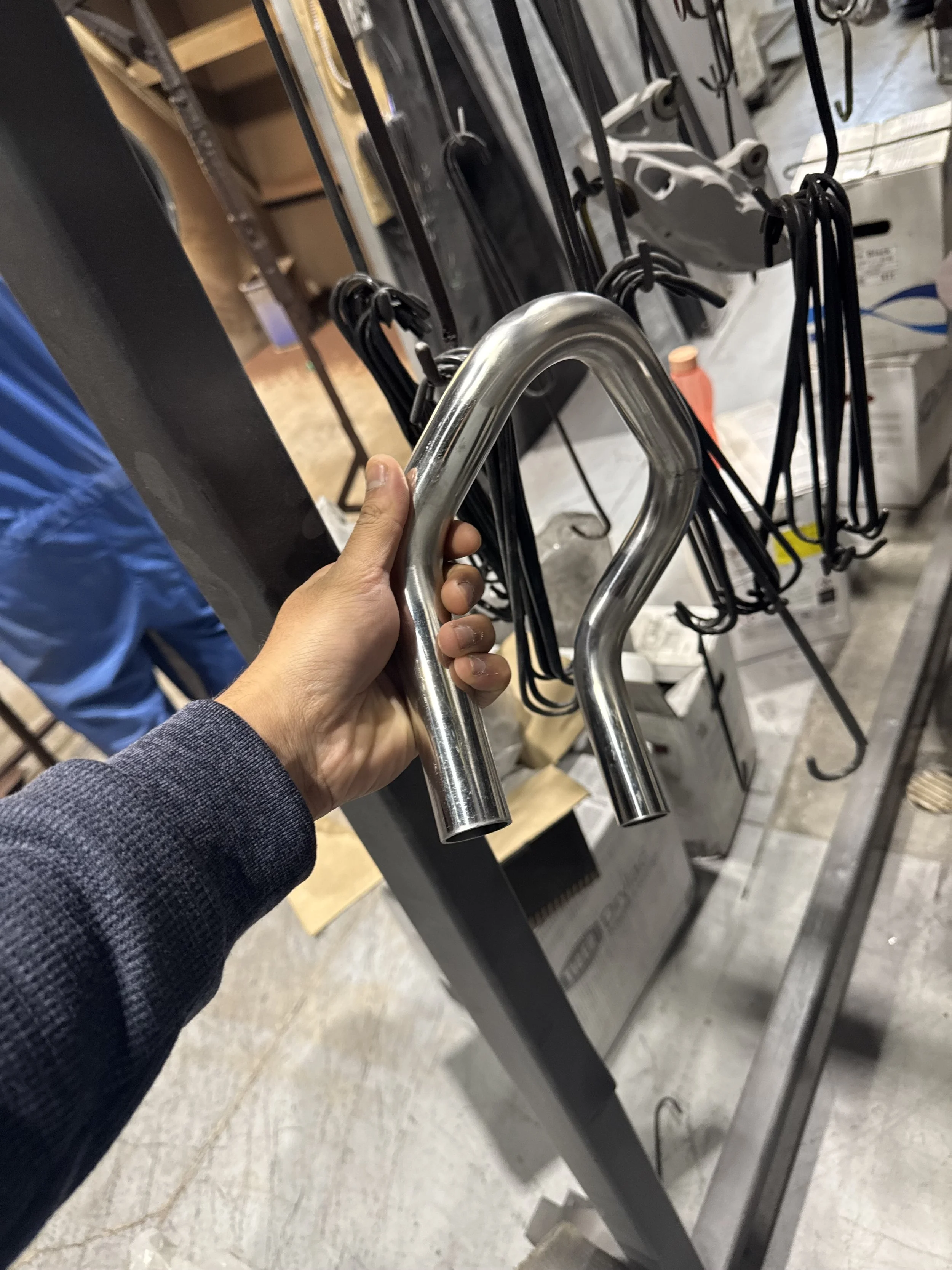 Person holding a stainless steel U-shaped handle in a hardware or home improvement store aisle.