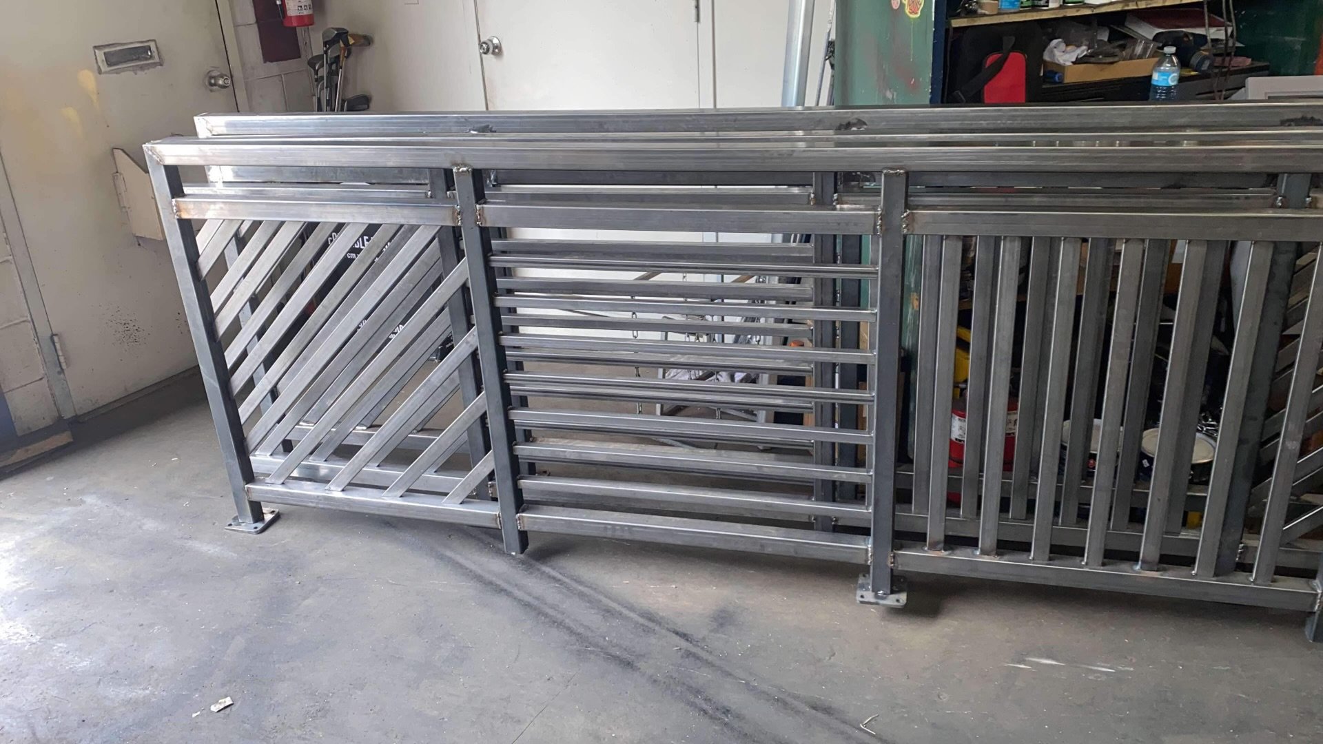 Metal racks with multiple shelving levels in a workshop, placed on a concrete floor.