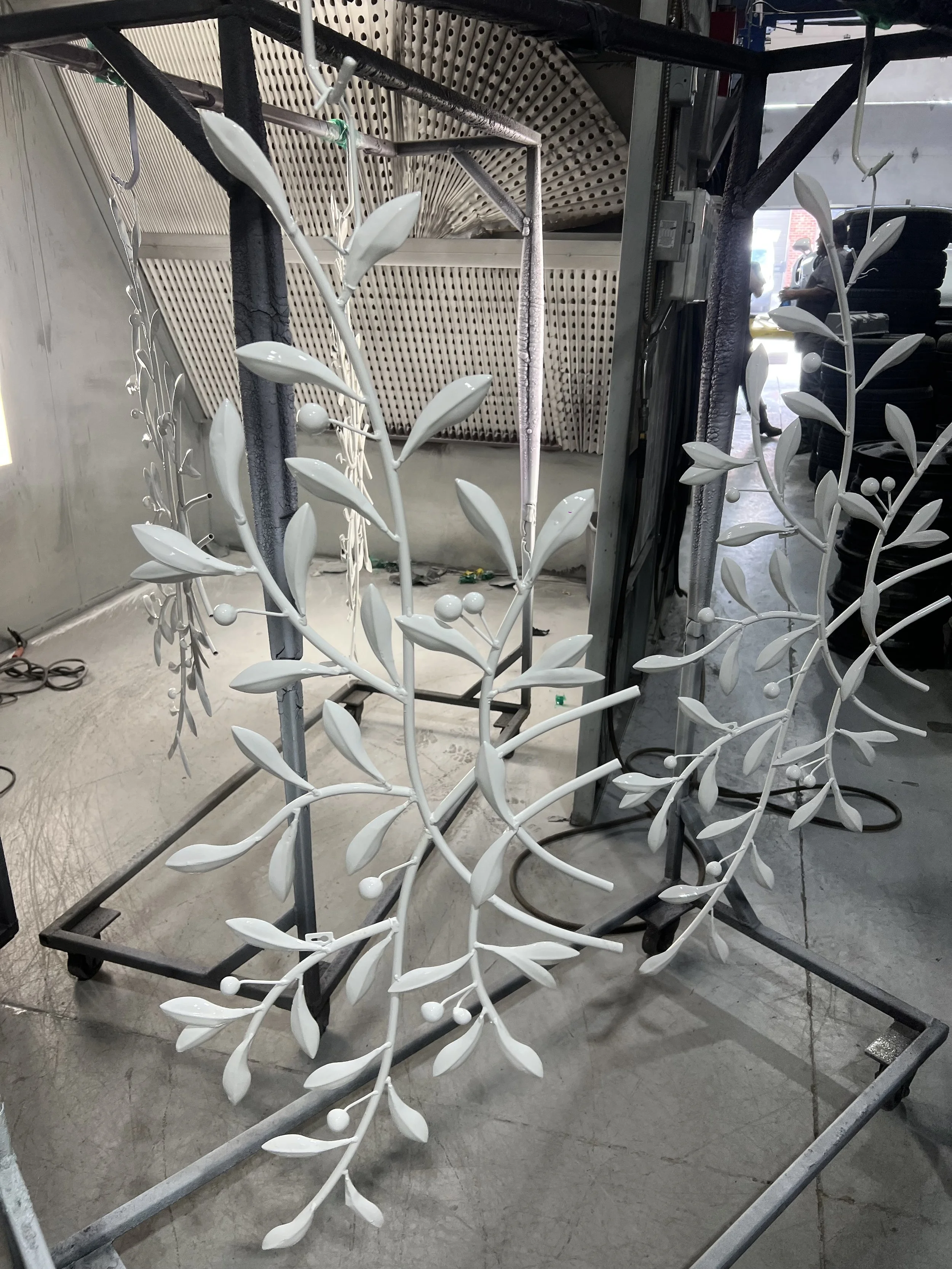 White decorative metal leaf and berry wreath in a workshop environment.