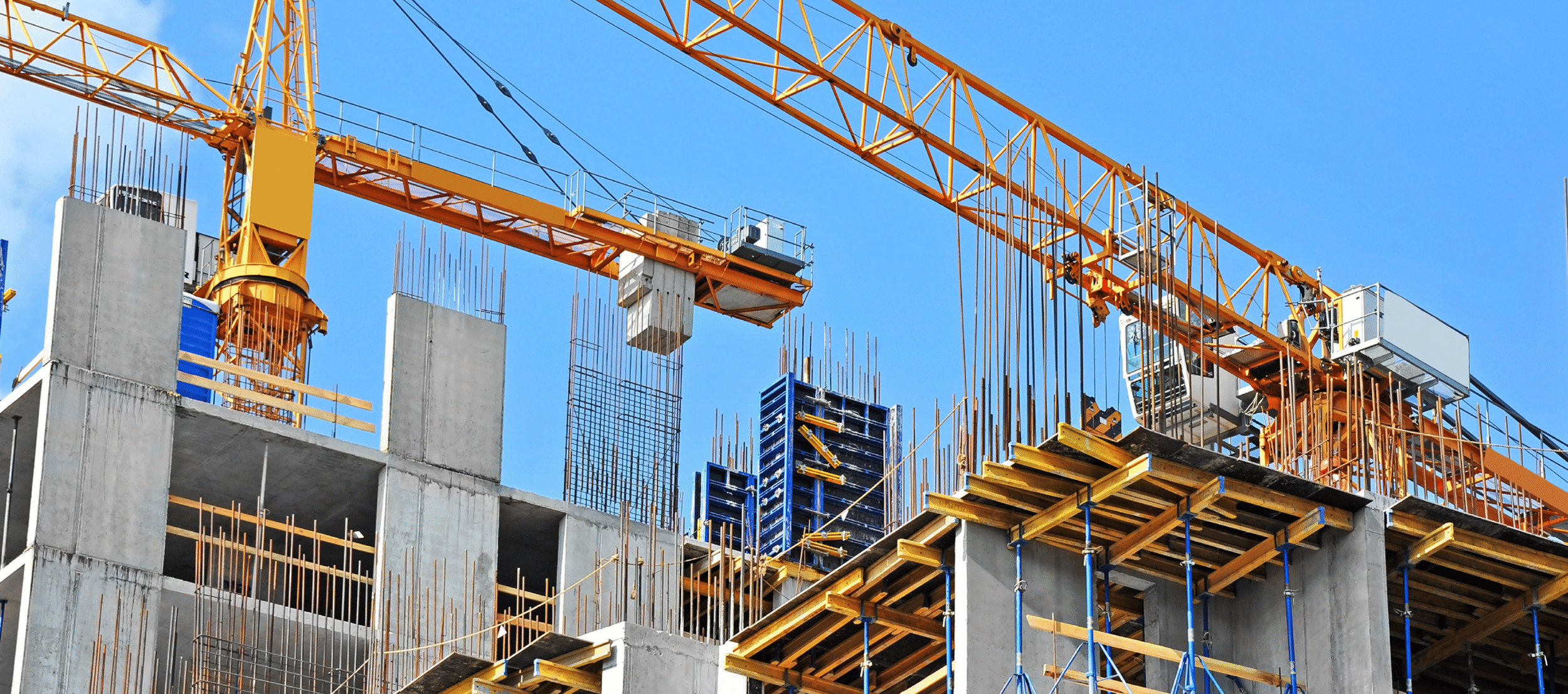 Construction site with a large yellow crane, concrete building framework, steel reinforcements, and temporary wooden and metal supports under a clear blue sky.