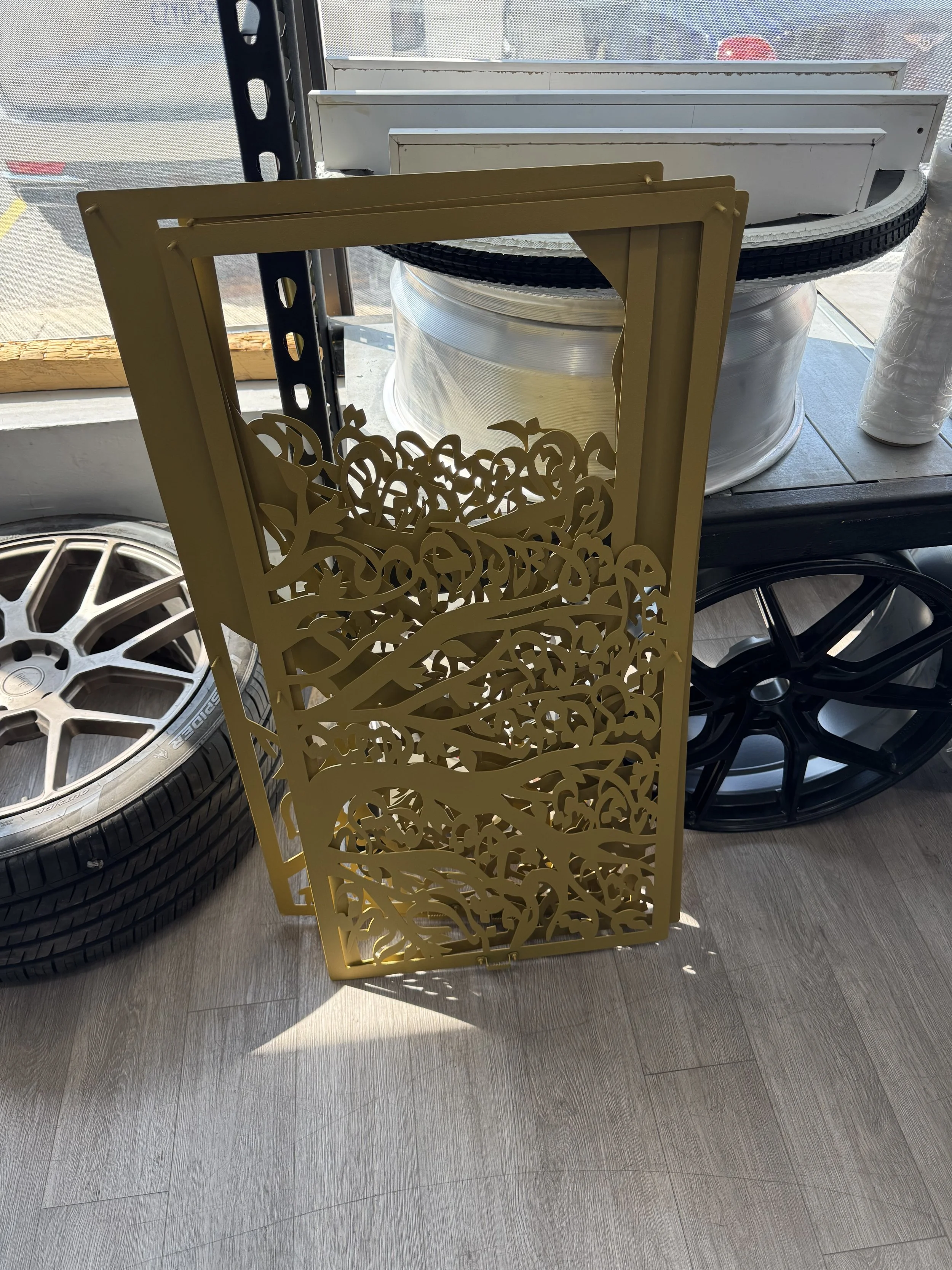 A gold-colored decorative metal panel with an intricate tree branch pattern.