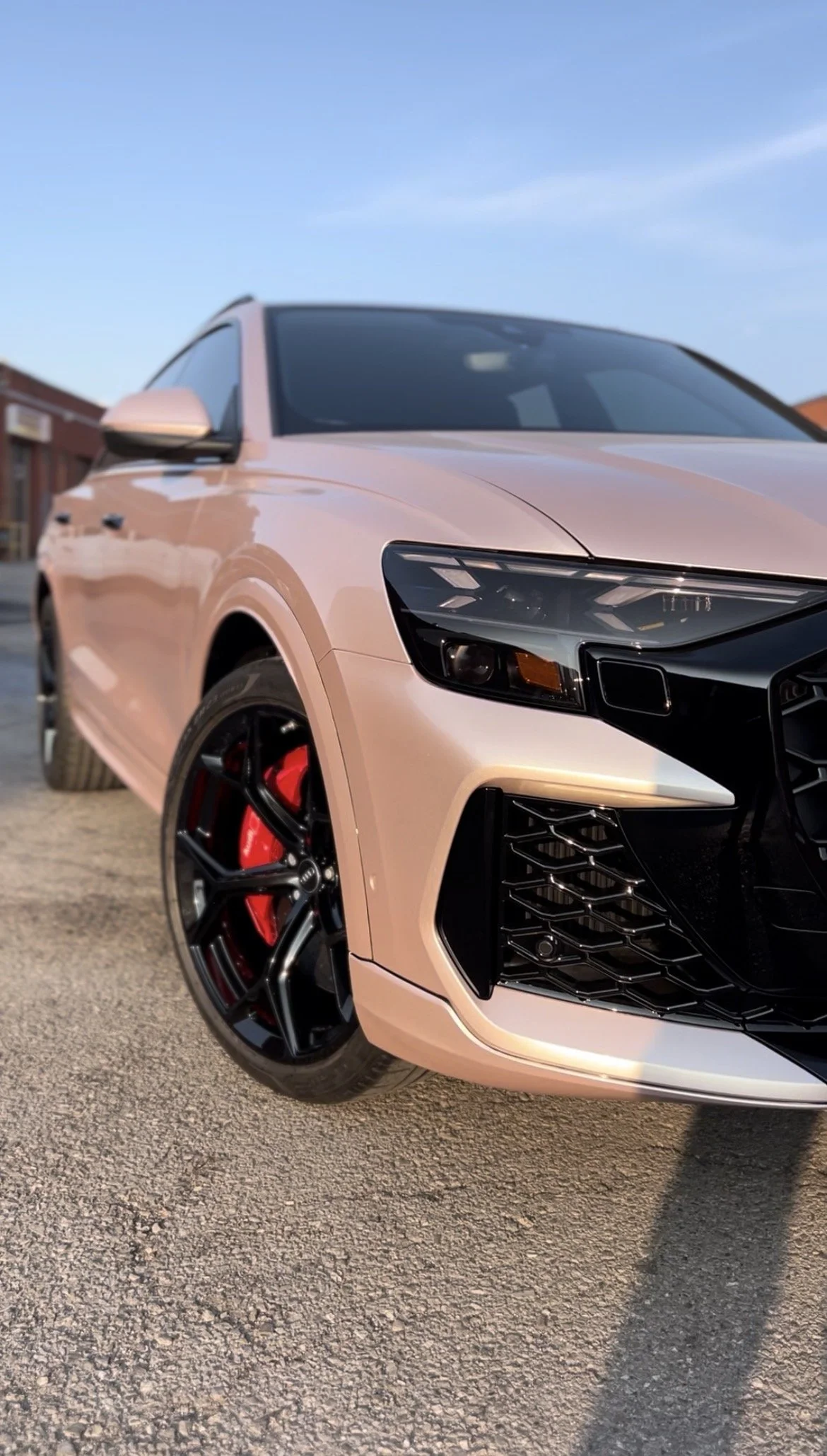 Pink sports sedan with black wheels and red brake calipers parked on a street during daytime.