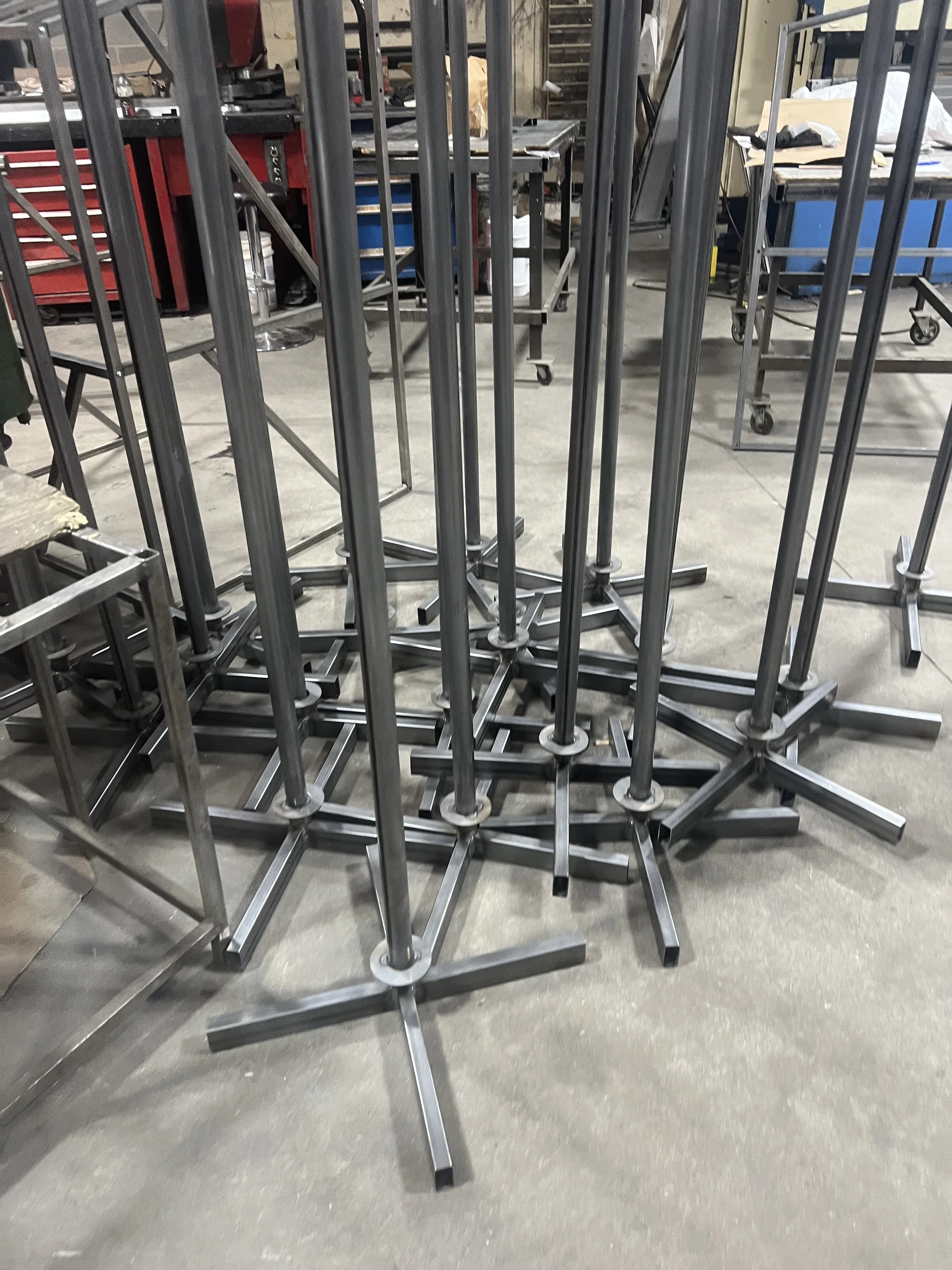 Several metal easels or stands stacked and leaning together in a workshop or industrial space.