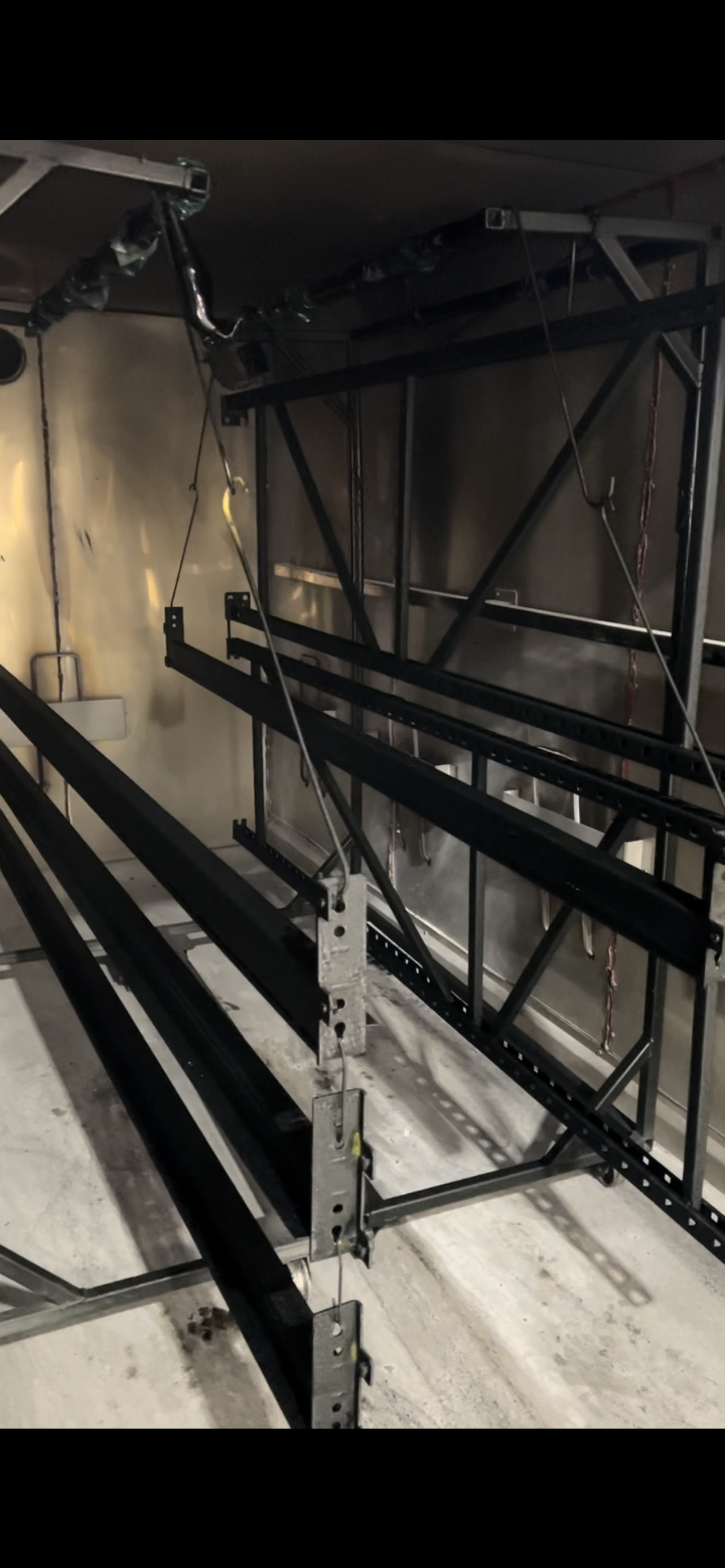 Metal framework and cables are attached to a ceiling, possibly for construction or installation work.