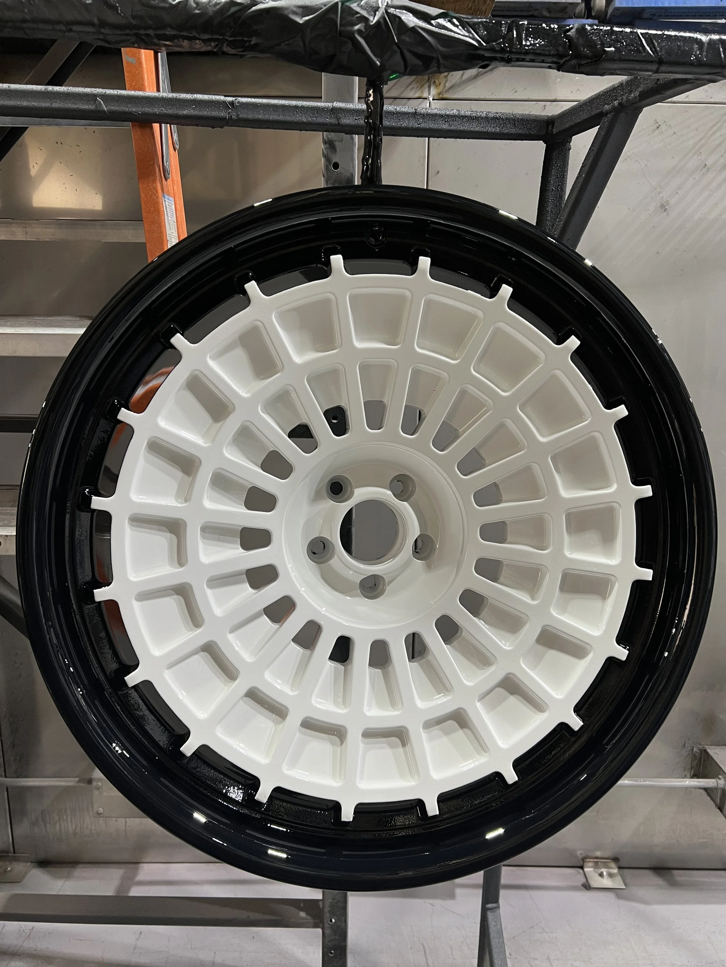 A close-up view of a black and white car wheel rim mounted on a display stand.