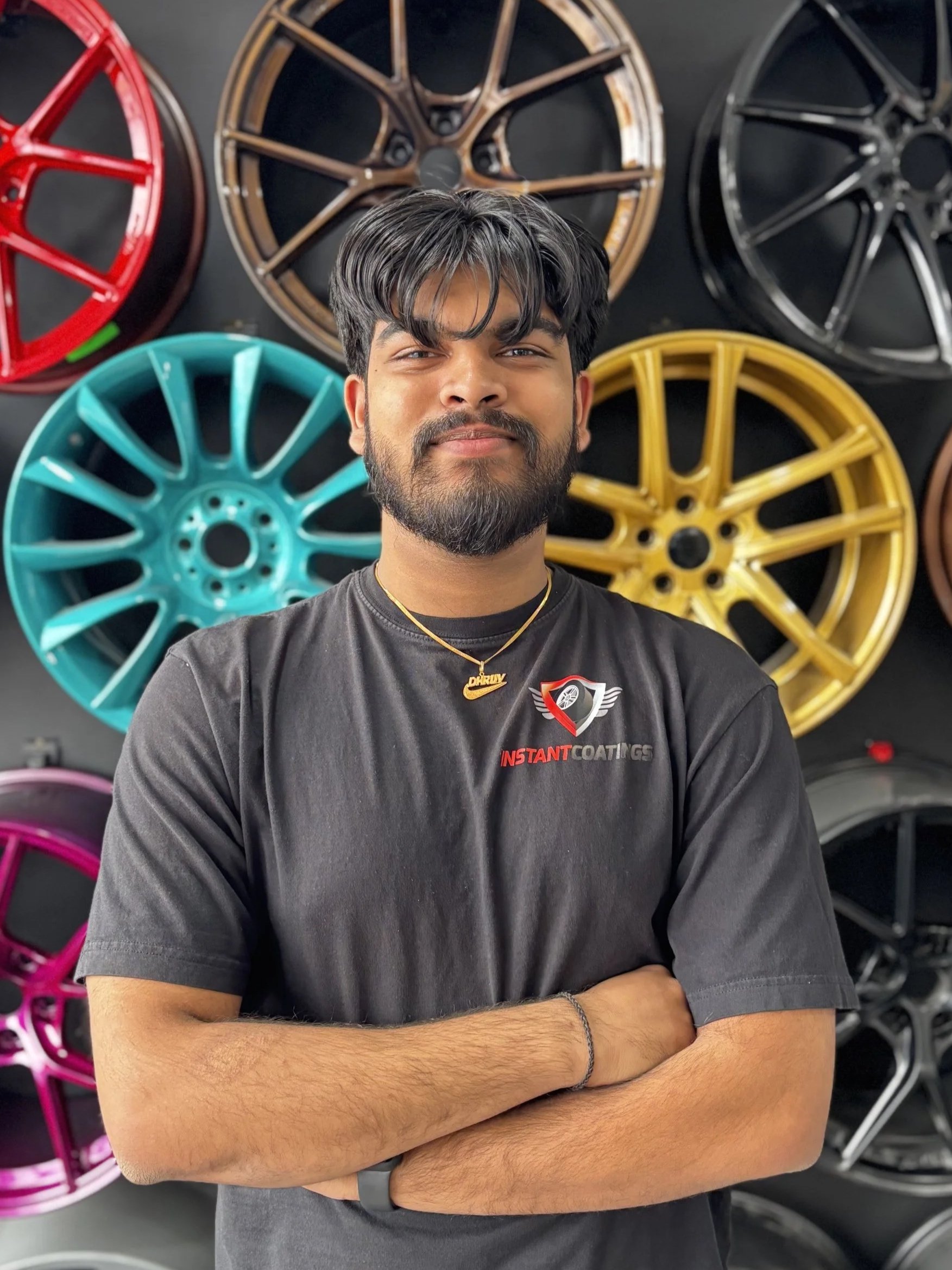 A woman with black shoulder-length hair smiling in front of greenery.