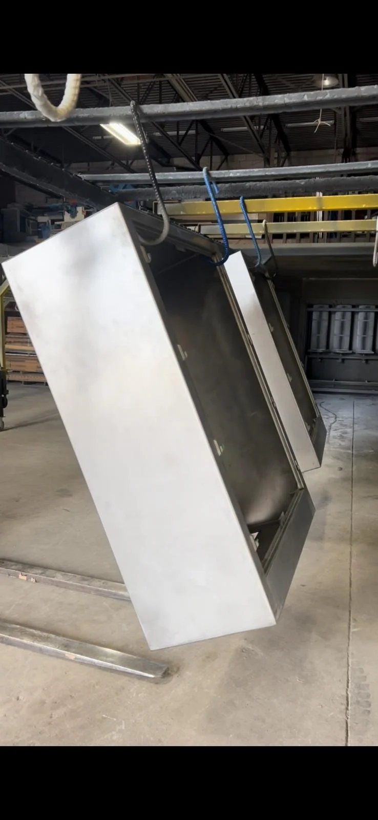 Steel commercial refrigerator door hanging upside down in a warehouse.