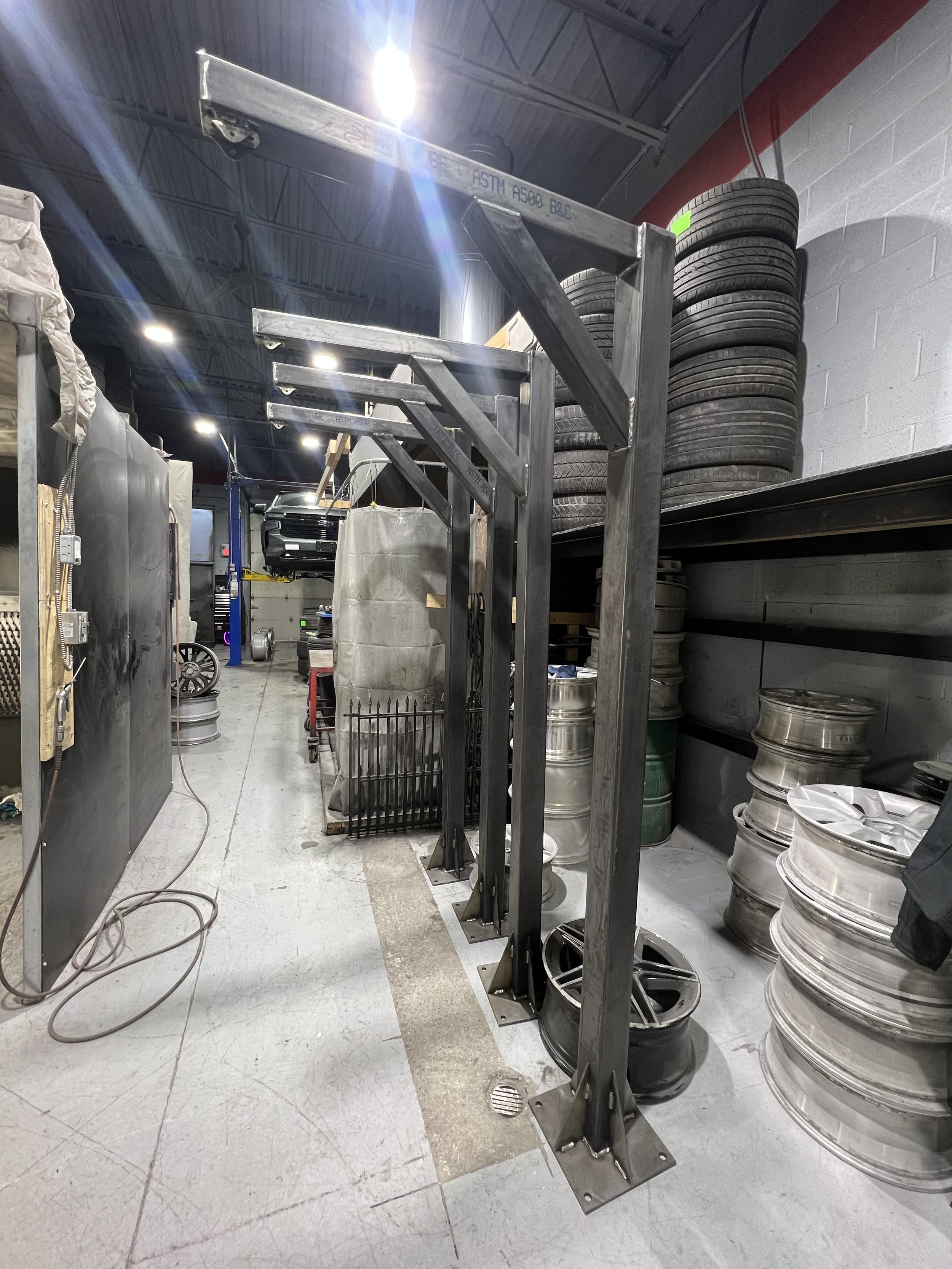 Garage or workshop with car lift and stacks of tires and rims.