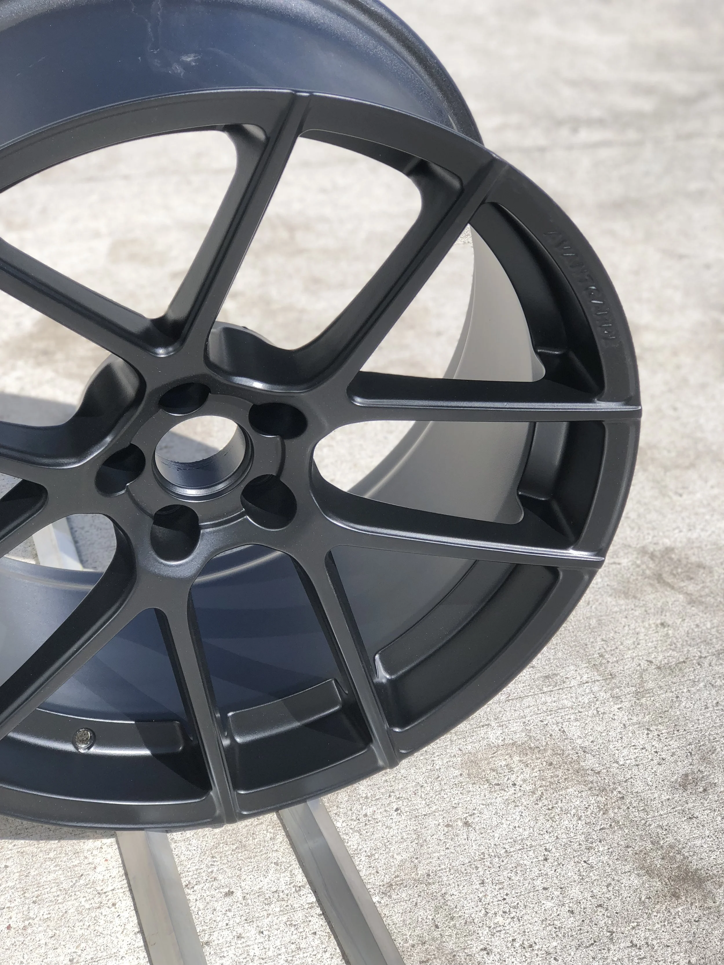 A black car wheel rim leaning against a light-colored surface.