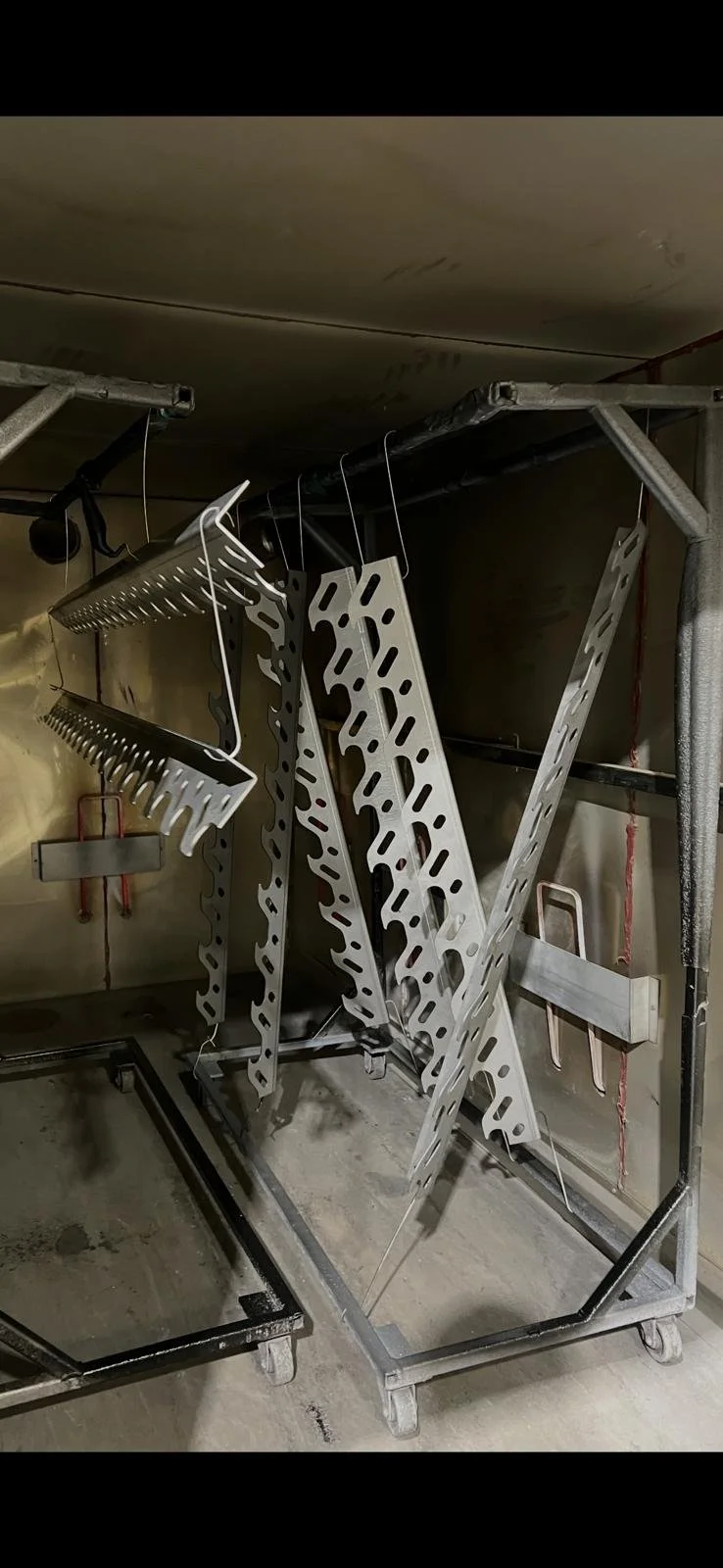 Metal racks and hangers on a wheeled metal cart in a storage or industrial area.