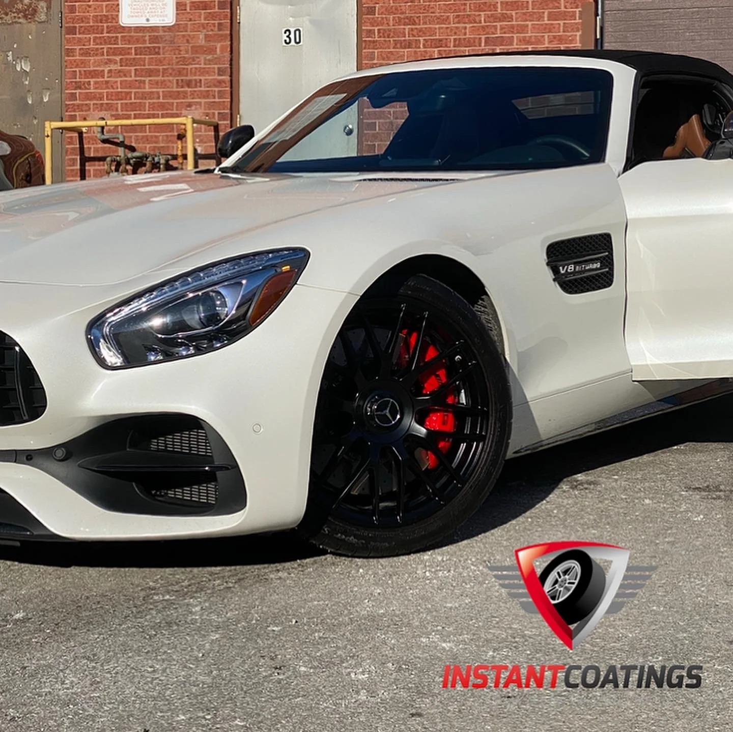 A white Mercedes-Benz sports car with black wheels and red brake calipers parked on a street, with a logo and text reading 'Instant Coatings' at the bottom right corner.