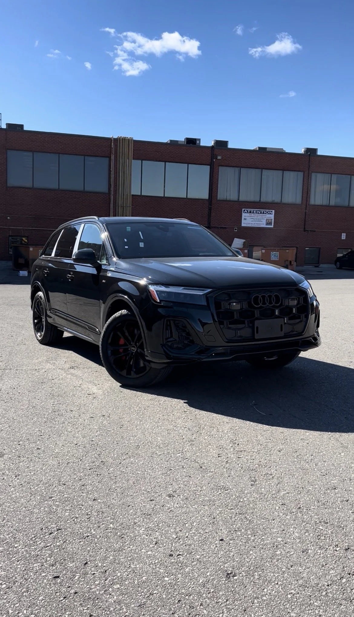 Black Audi SUV parked in an outdoor lot under a blue sky with some clouds.