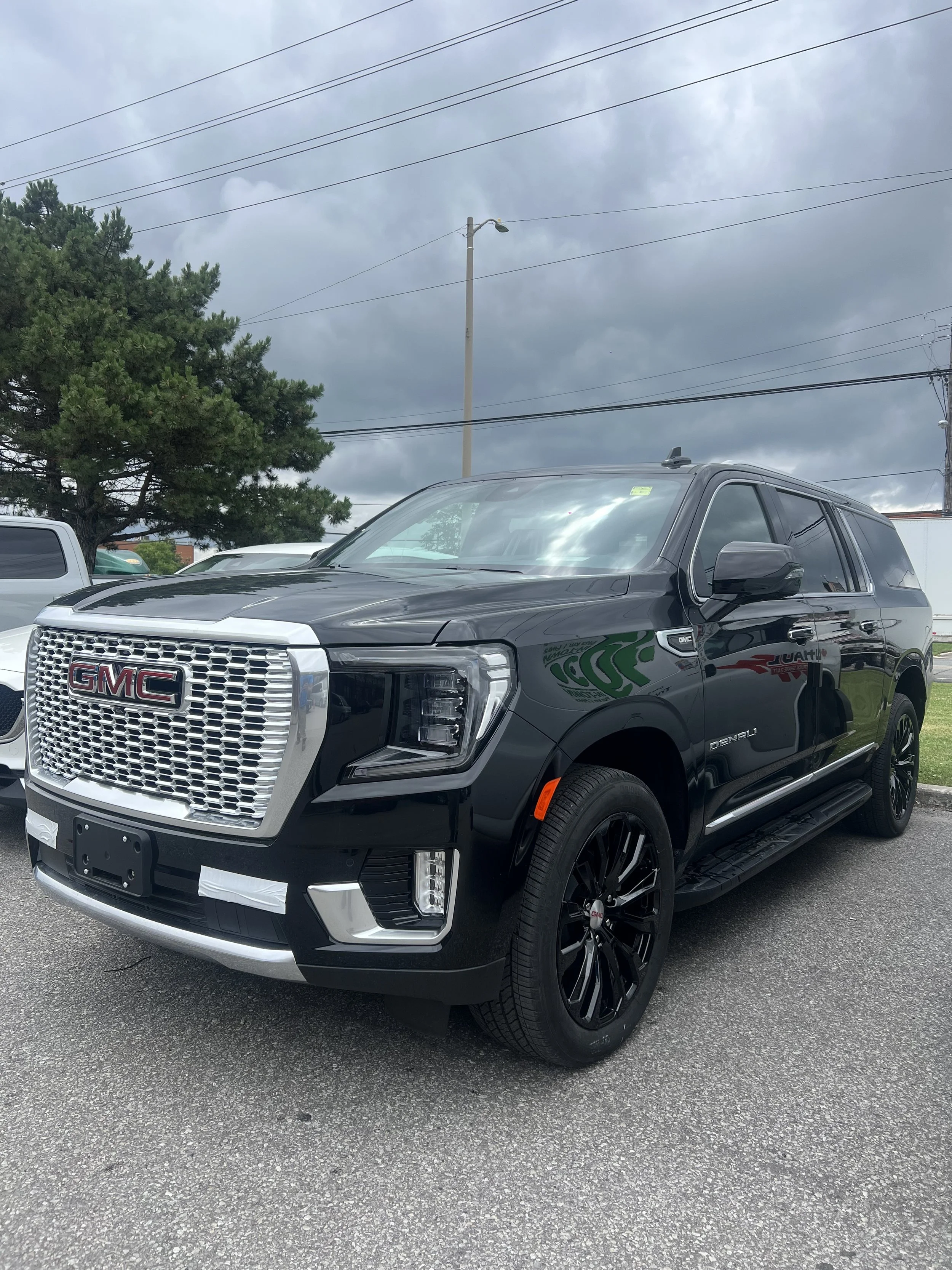 Black GMC Denali SUV parked in a lot on a cloudy day.