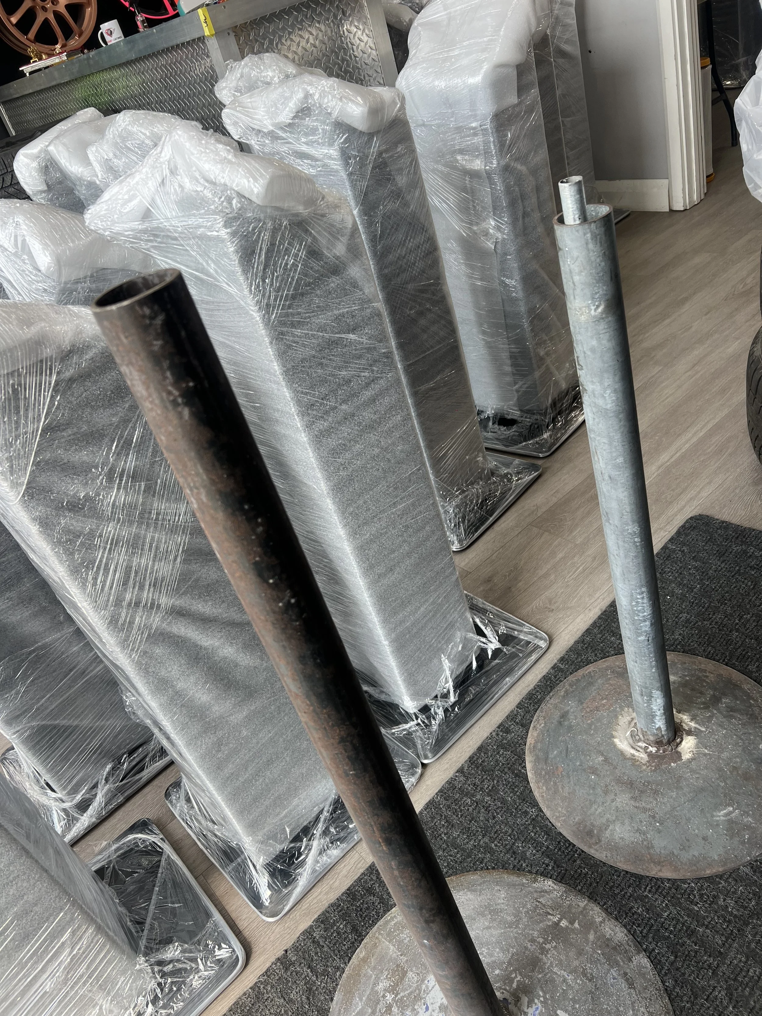 Metal poles resting on round bases in a hardware store with wrapped metal stands behind them.