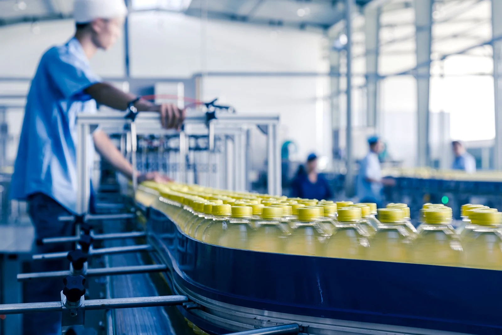 Workers in a factory assembling plastic bottles on a conveyor belt.