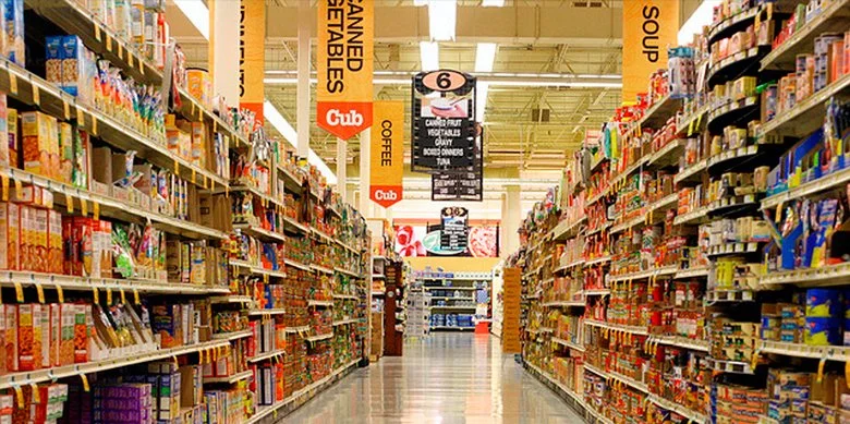 View of store aisles stocked with food products, with signage indicating bakery and soup sections.