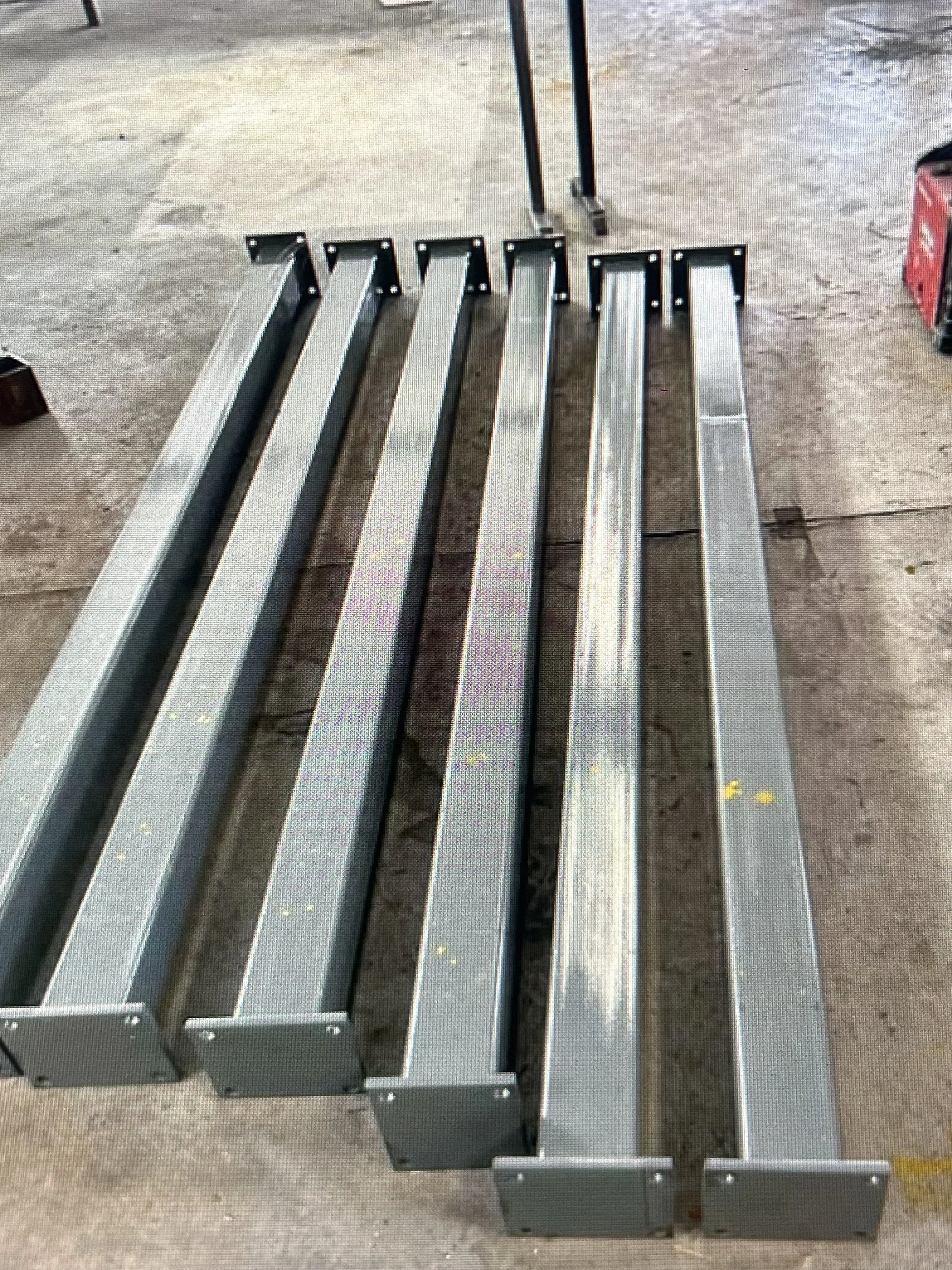Steel bench frame with metal slats on a concrete floor.