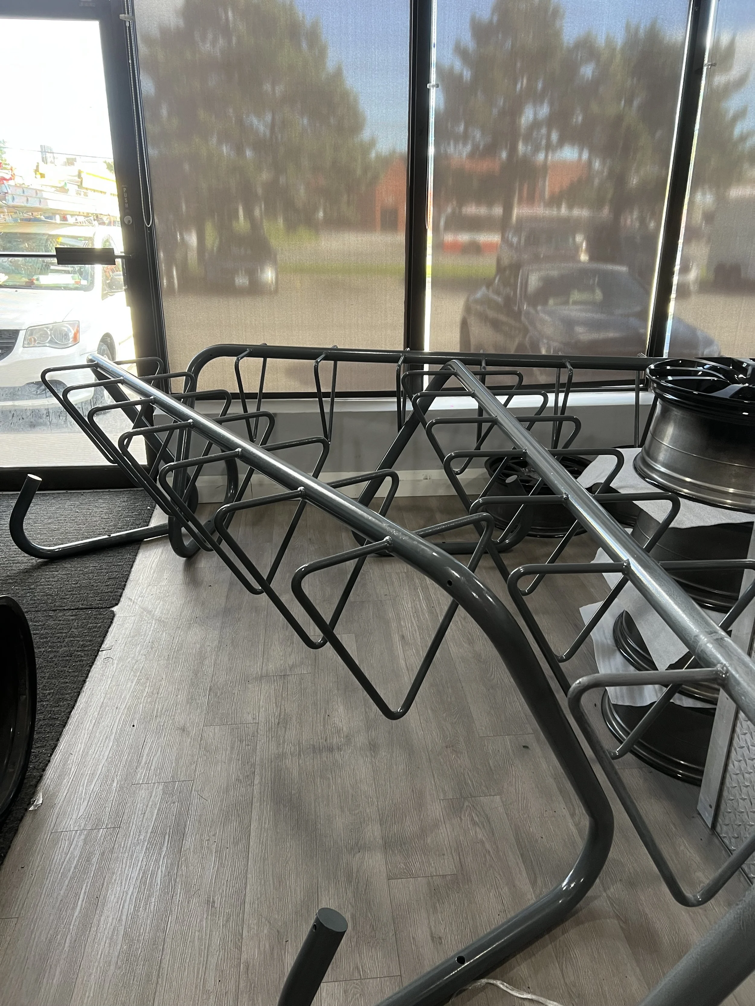 Upside-down metal shopping cart inside store near large window with cars outside.