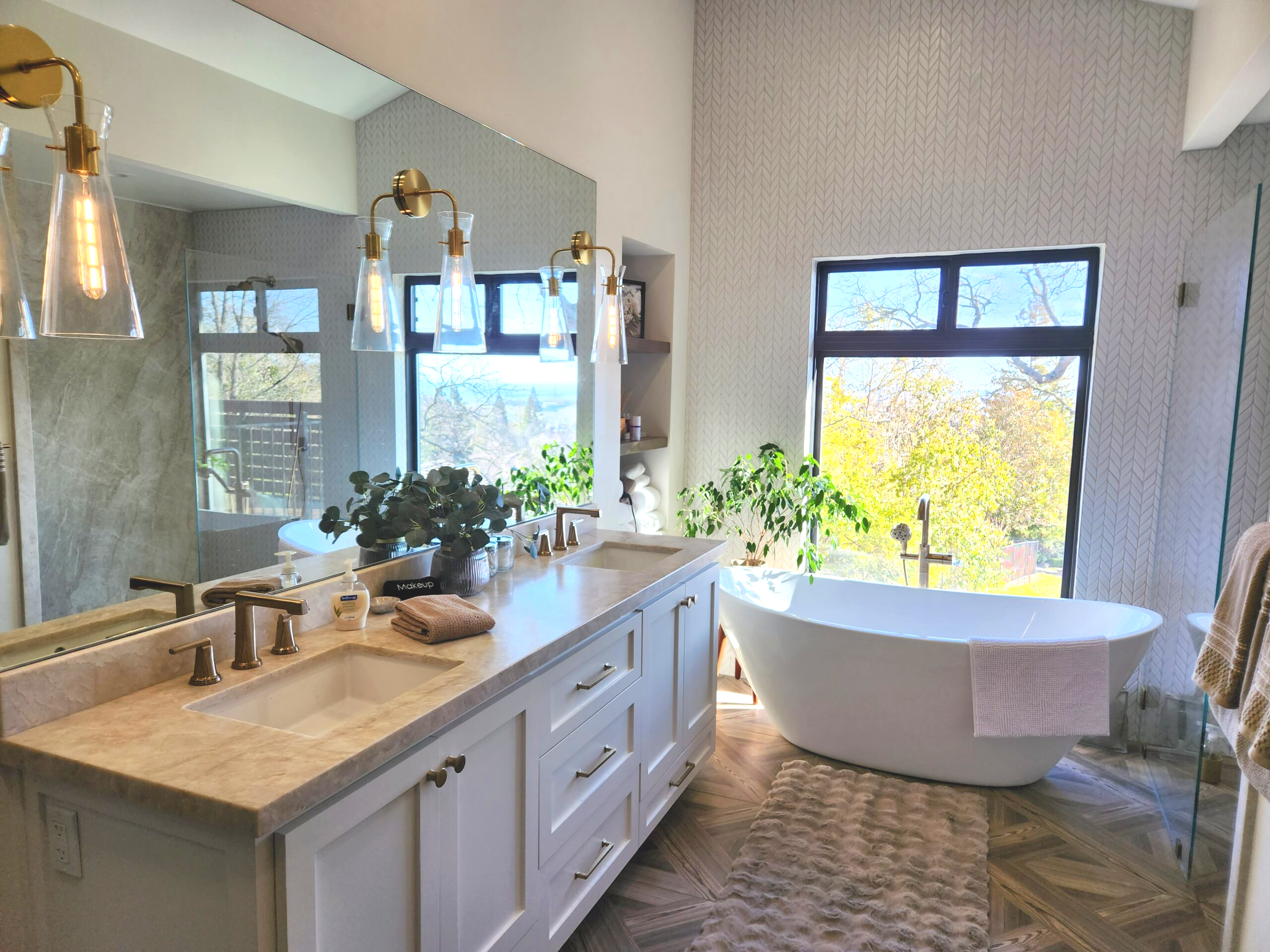 Bathroom with a large window, free-standing bathtub, and a double sink vanity with a mirror and pendant lights.