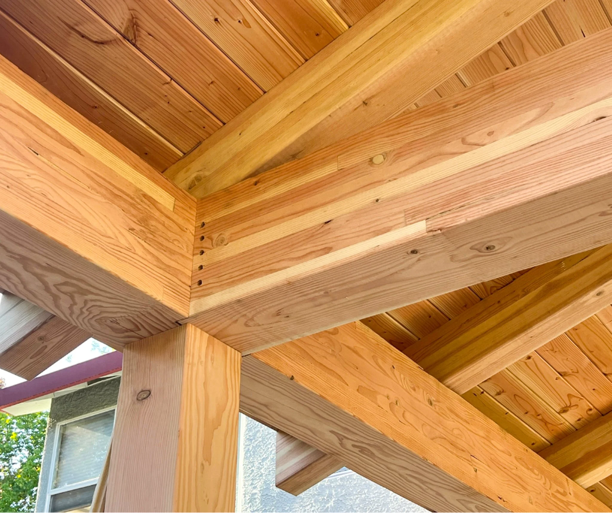Close-up of a wooden porch roof showing the corner joint and support beams.
