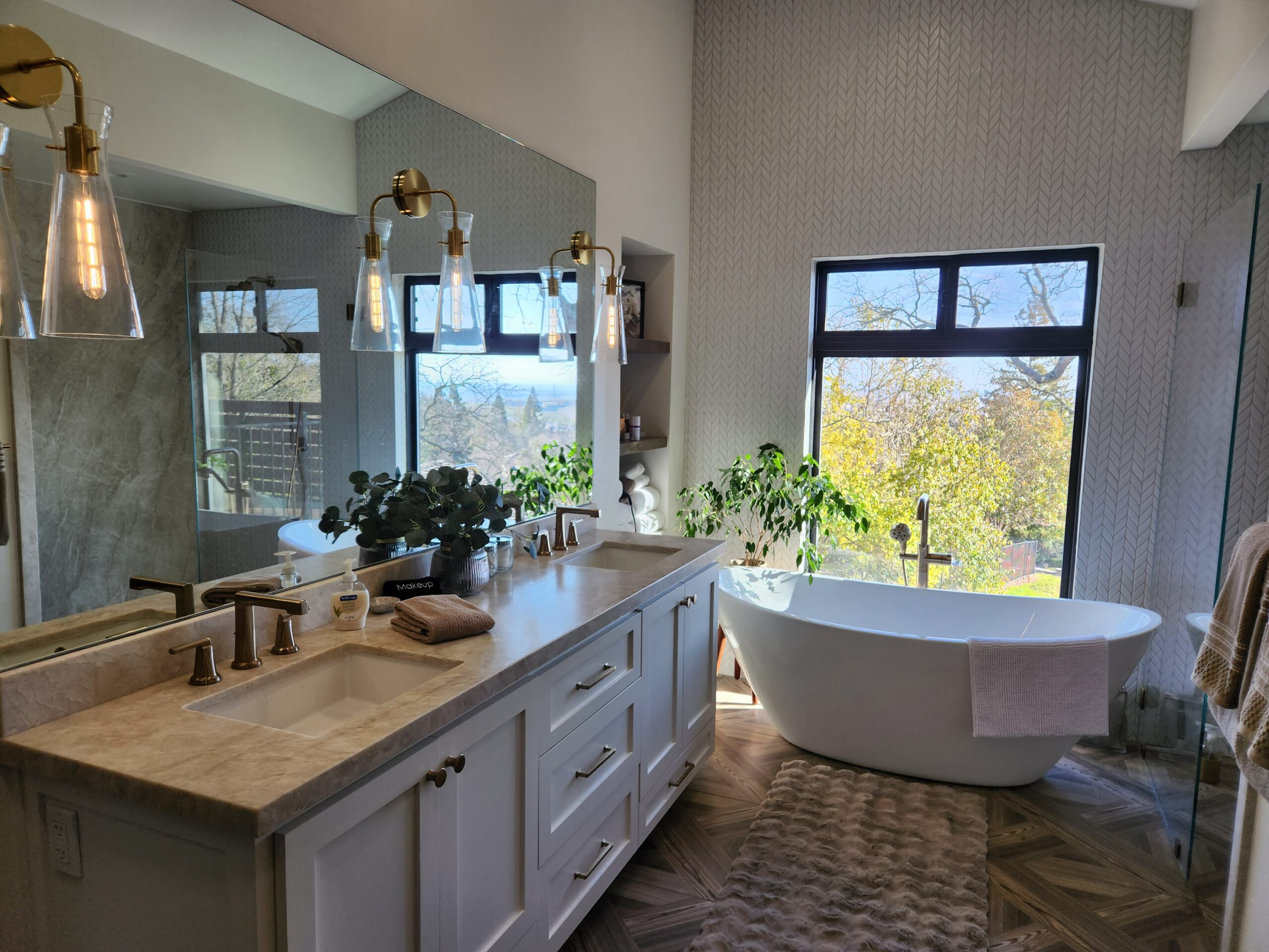 Bathroom with a large window, free-standing bathtub, and a double sink vanity with a mirror and pendant lights.