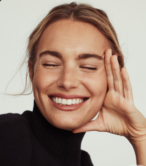 Smiling woman with closed eyes, resting her head on her hand