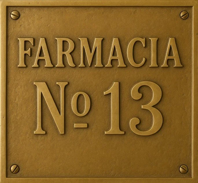A brass plaque with the words 'FARMACIA No 13' engraved on it, mounted on a surface with four screws at each corner.