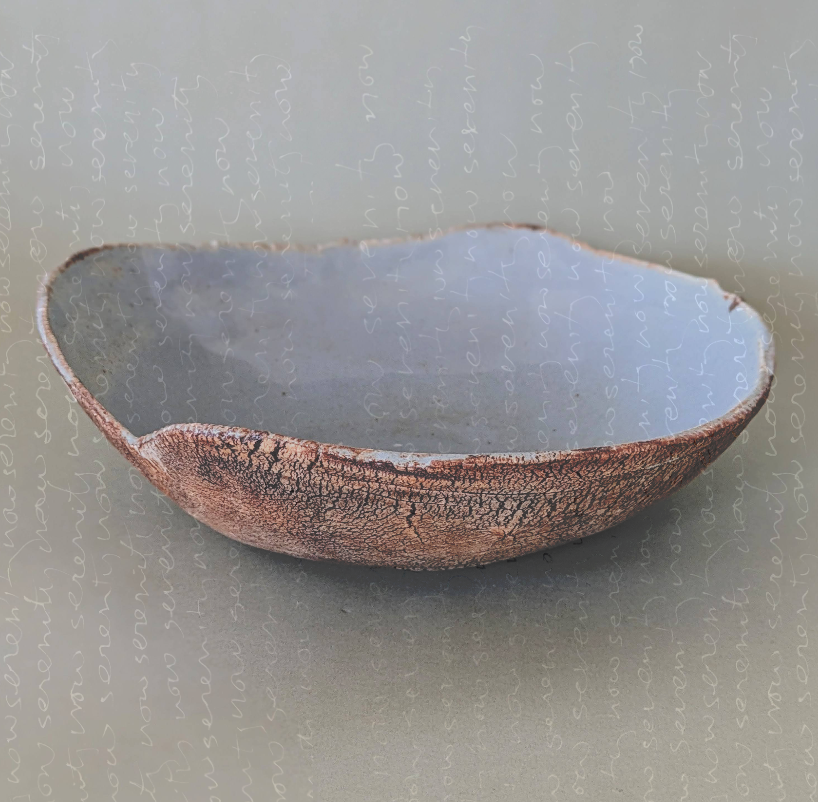 A ceramic bowl with a textured, crackled brown exterior and a smooth, gray interior, placed on a light gray surface.