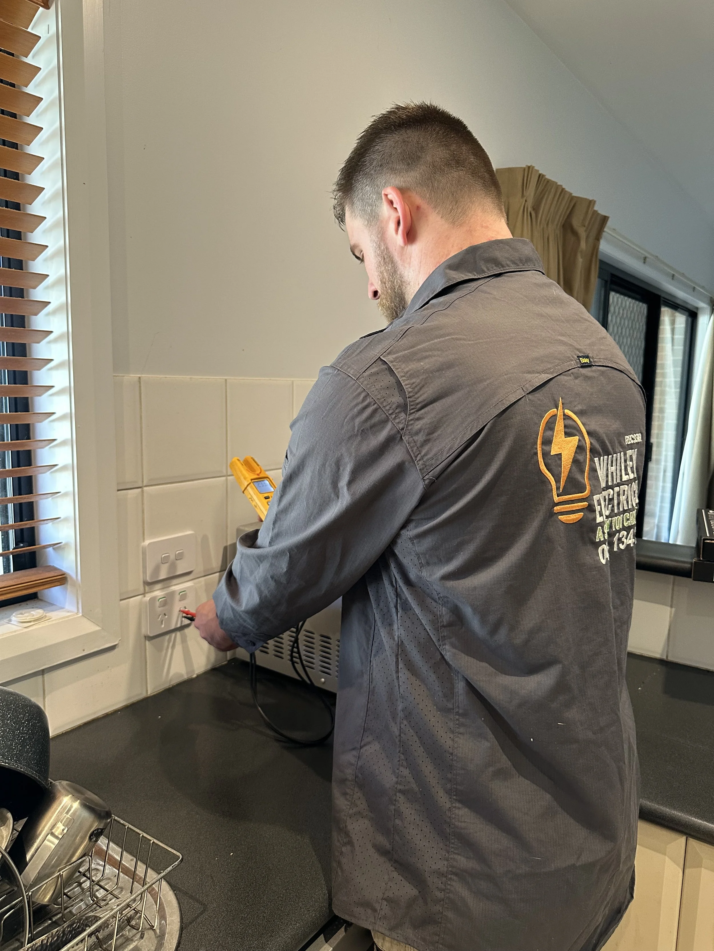 Man with beard fixing power outlet in kitchen - Whiley Electrical - Bendigo Electrician - Services