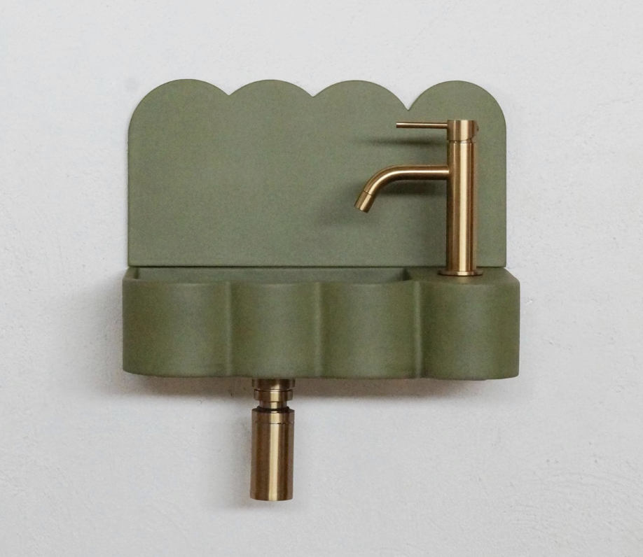 A wall-mounted green sink with a scalloped back and a bronze faucet.