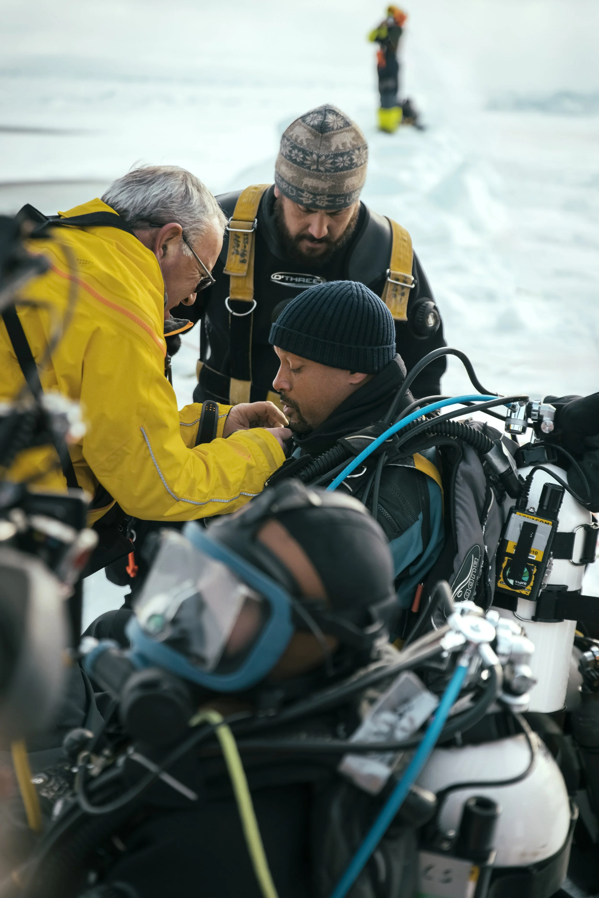 Rescue team assisting Will Smith with a breathing apparatus for scuba diving in a snowy environment. 