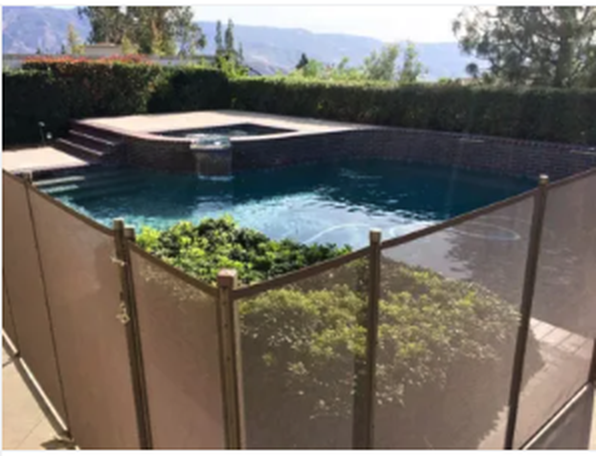 Residential swimming pool with a safety fence in a landscaped backyard