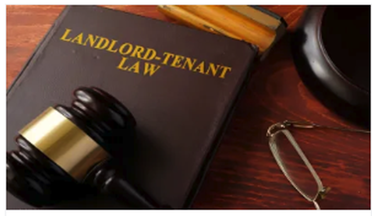 Landlord-tenant law book with a judge’s gavel and eyeglasses on a wooden desk