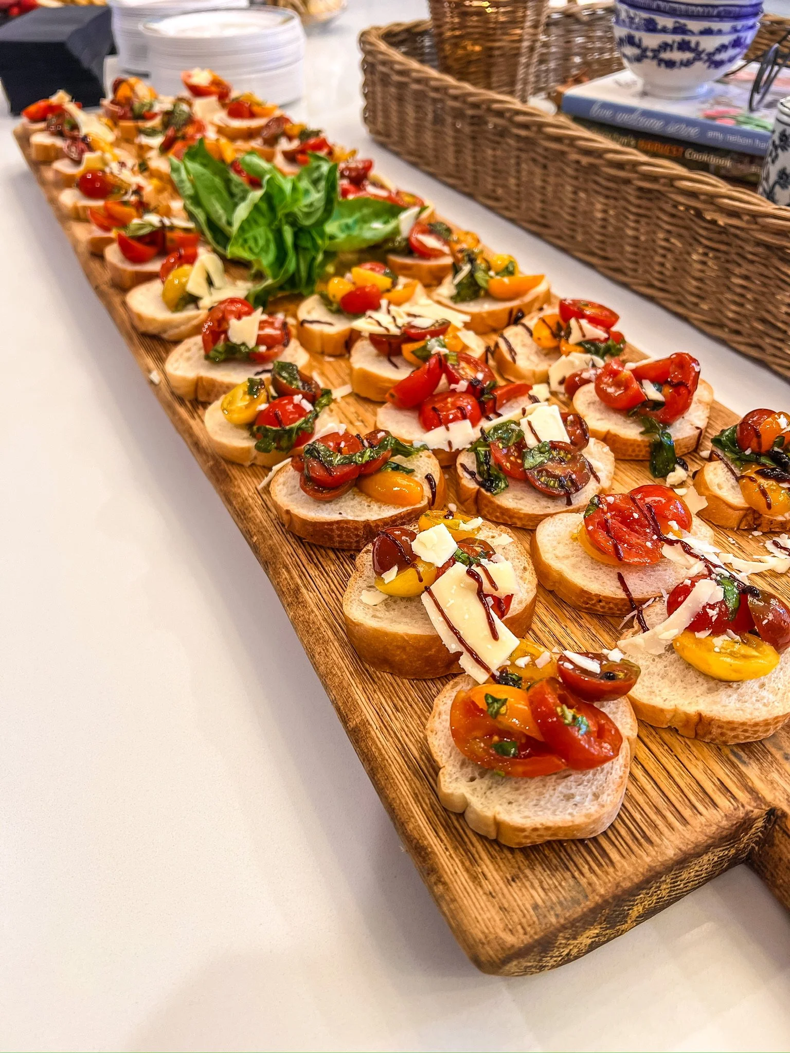 Assorted bruschetta on a wooden serving board with cherry tomatoes, basil, and cheese.