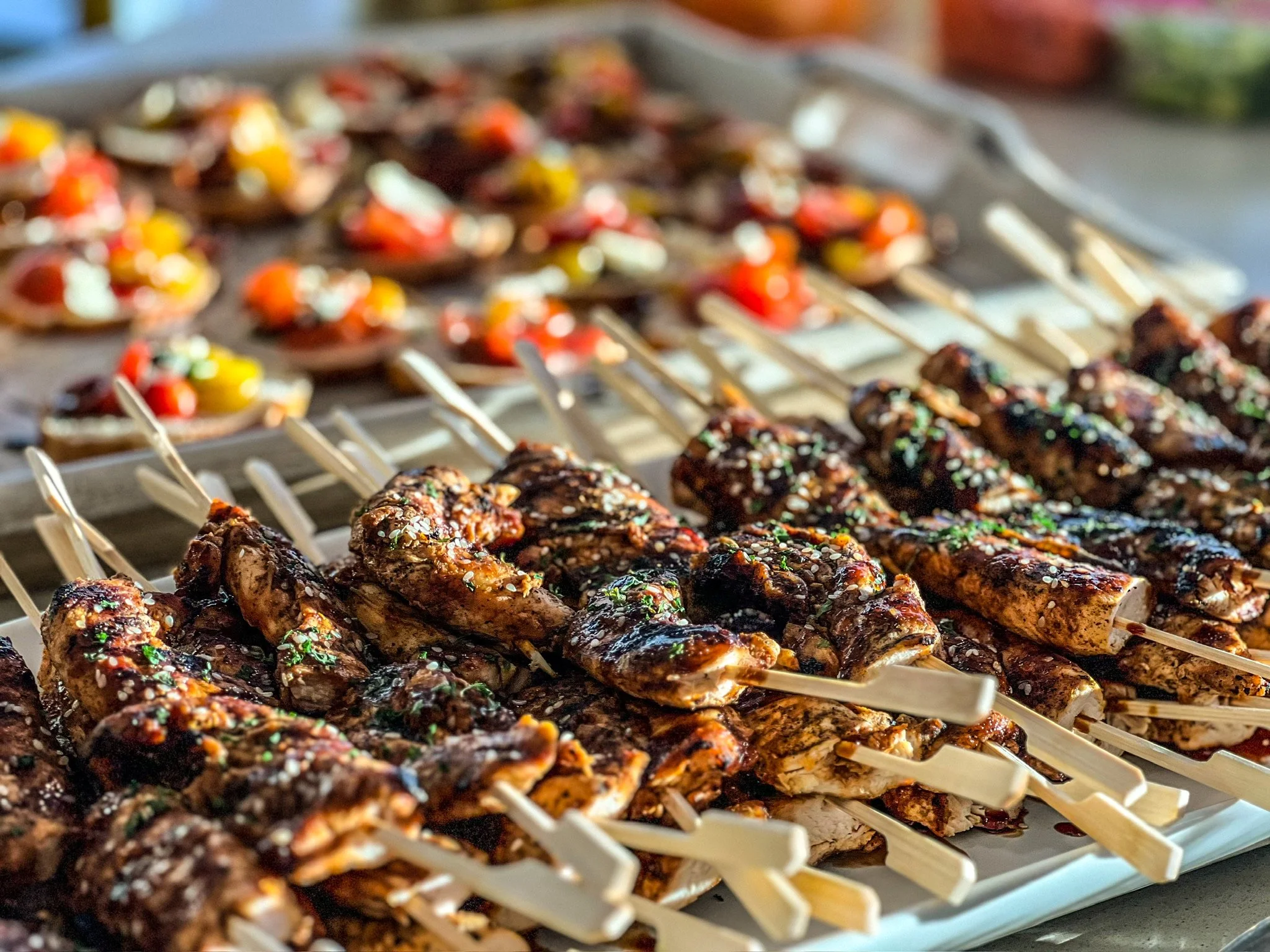 Close-up of grilled chicken skewers and assorted mini tacos on a platter.