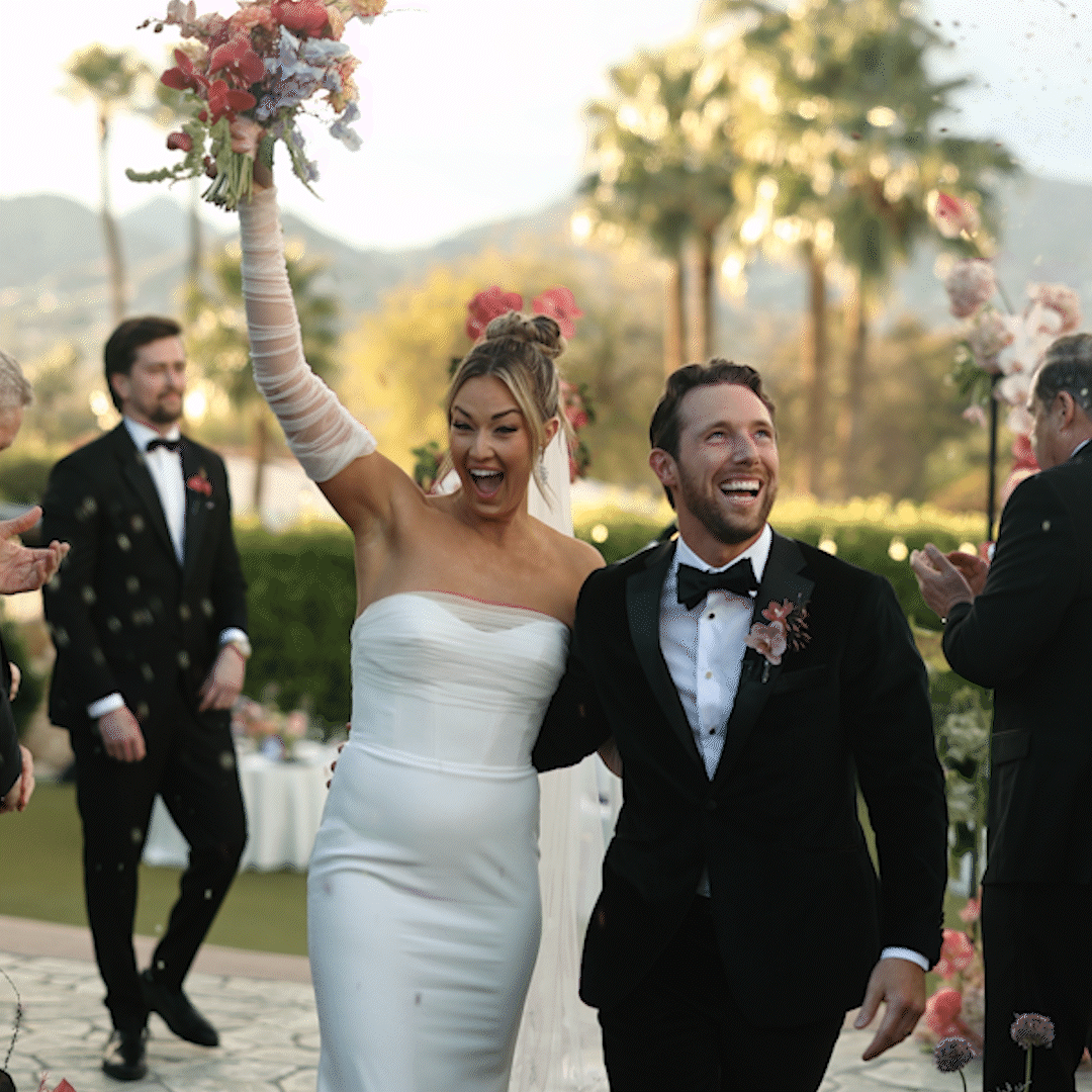 Bride and groom celebrating at their outdoor wedding, with guests clapping and cheering in the background, taken by phoenix wedding videographer.