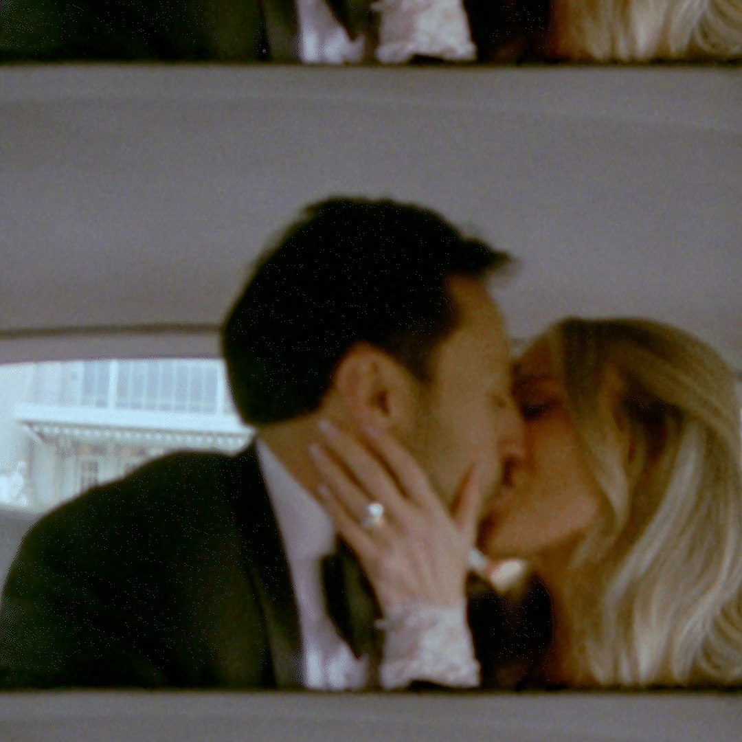 A couple kissing in an elevator, with the woman holding the man's face and wearing a wedding ring filmed by destination wedding videographer.