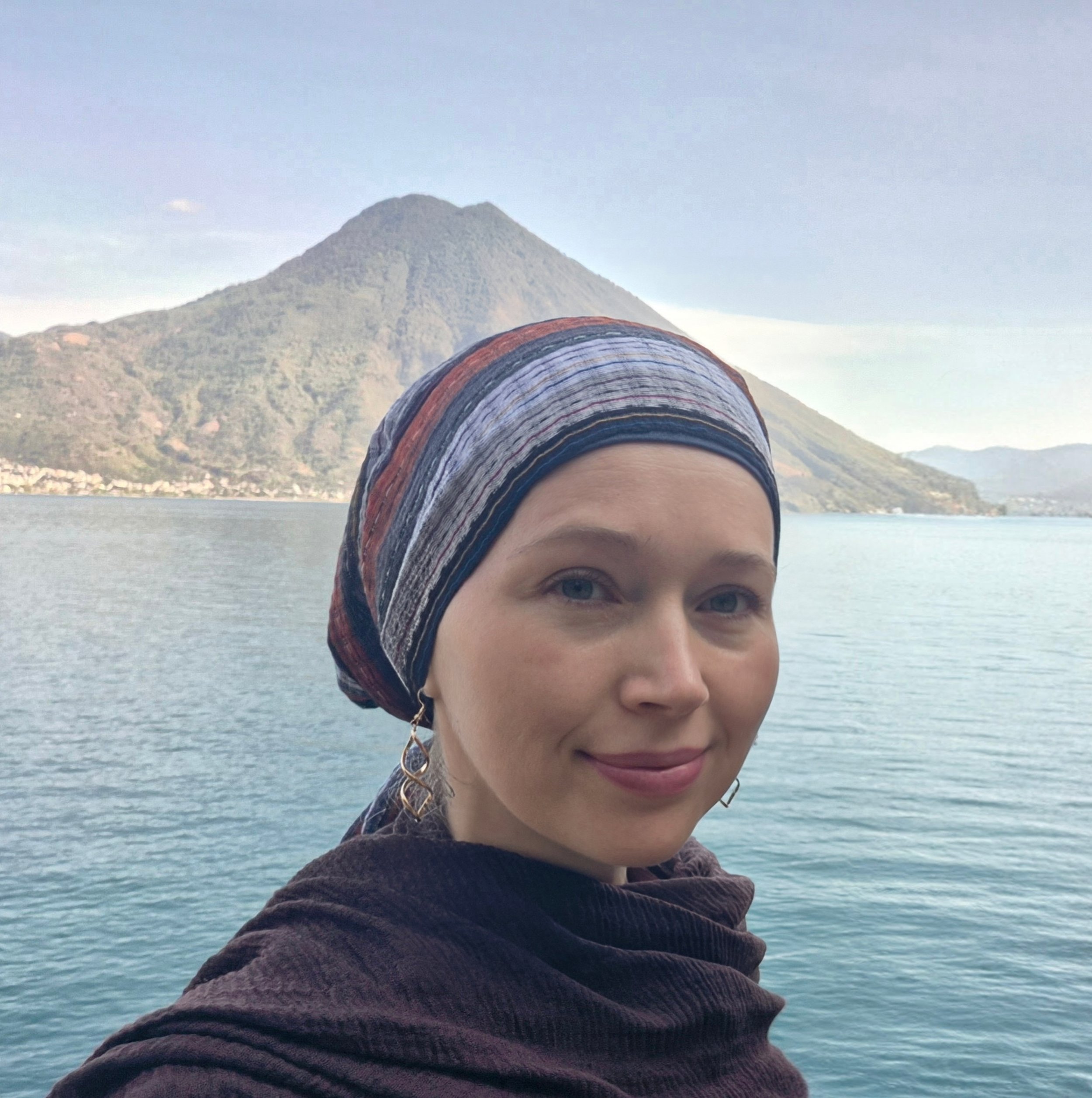 Kirstie Smith — Midwife — taking a selfie in front of a lake with mountains in the background.