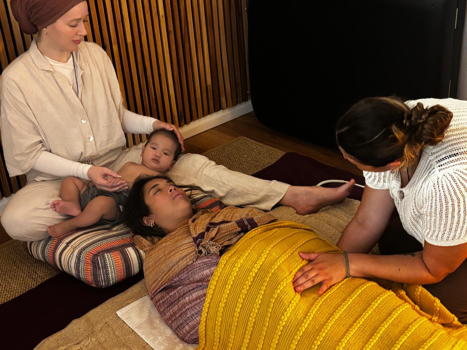 midwife practising craniosacral therapy on a women and her child laying down