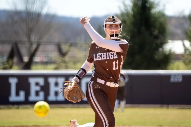 Lehigh softball player in a brown uniform with the number 11, wearing a helmet and glove, during a game at the field.
