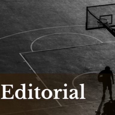 An indoor basketball court with a player standing near the basket.